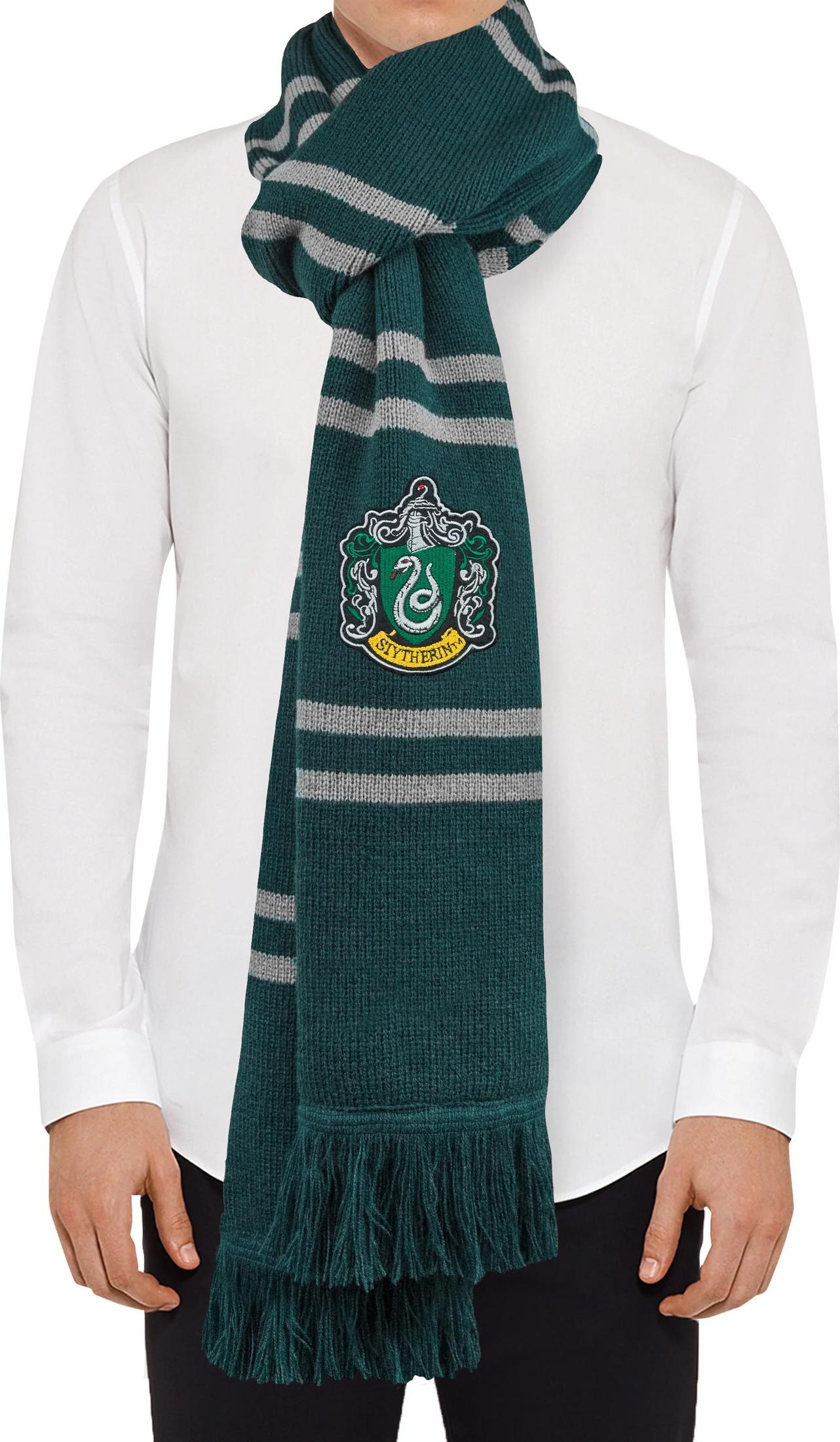 Ein Mann trägt einen dunkelgrünen Schal mit grauen Streifen und dem Slytherin-Wappen.