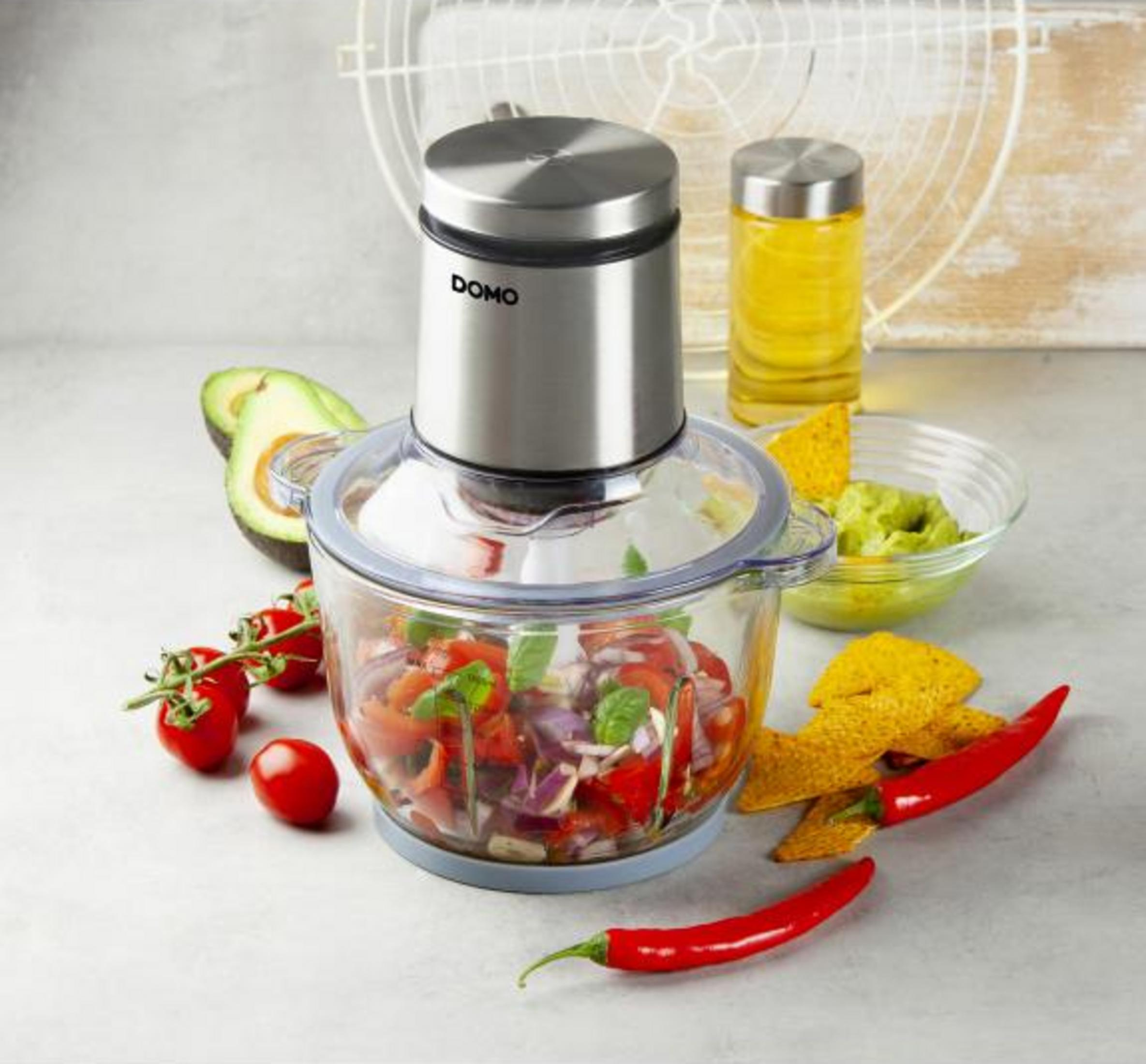 Un tritatutto con ingredienti come pomodori, cipolle, avocado e peperoncini.