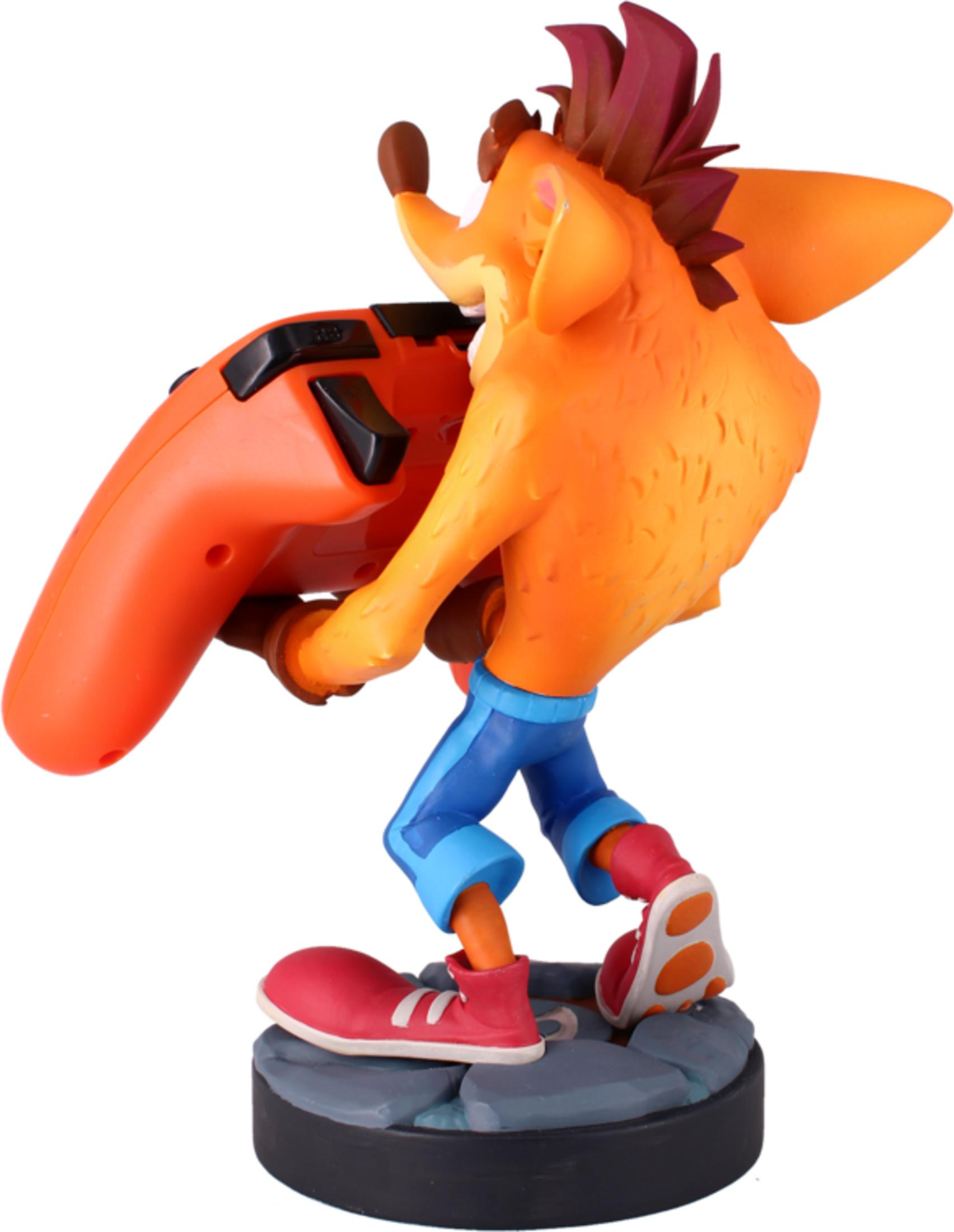 Statua di Crash Bandicoot che tiene un controller arancione, indossa pantaloni blu e scarpe rosse.
