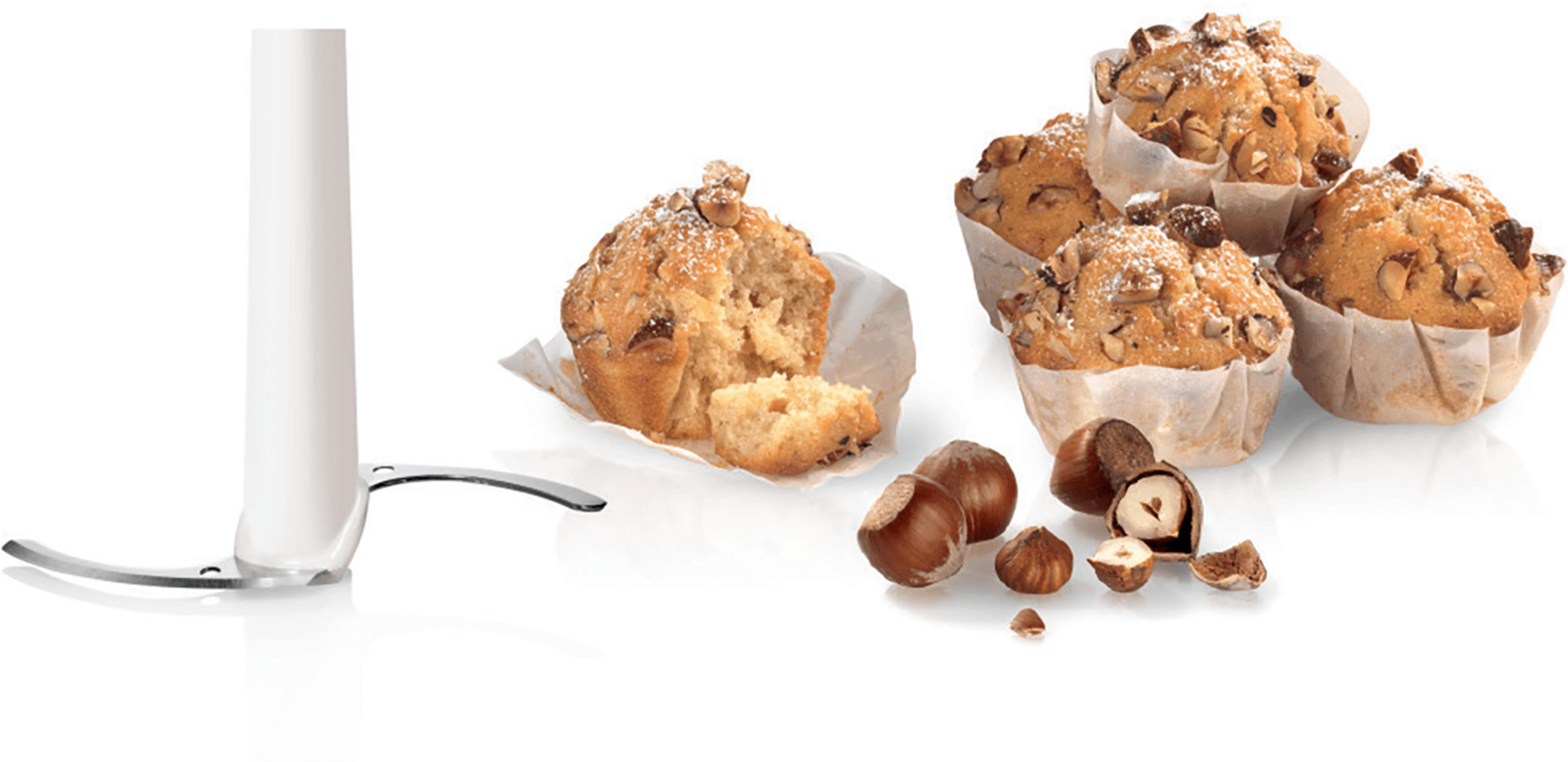 Un accesorio de licuadora con cuchillas junto a muffins de avellana y avellanas enteras.