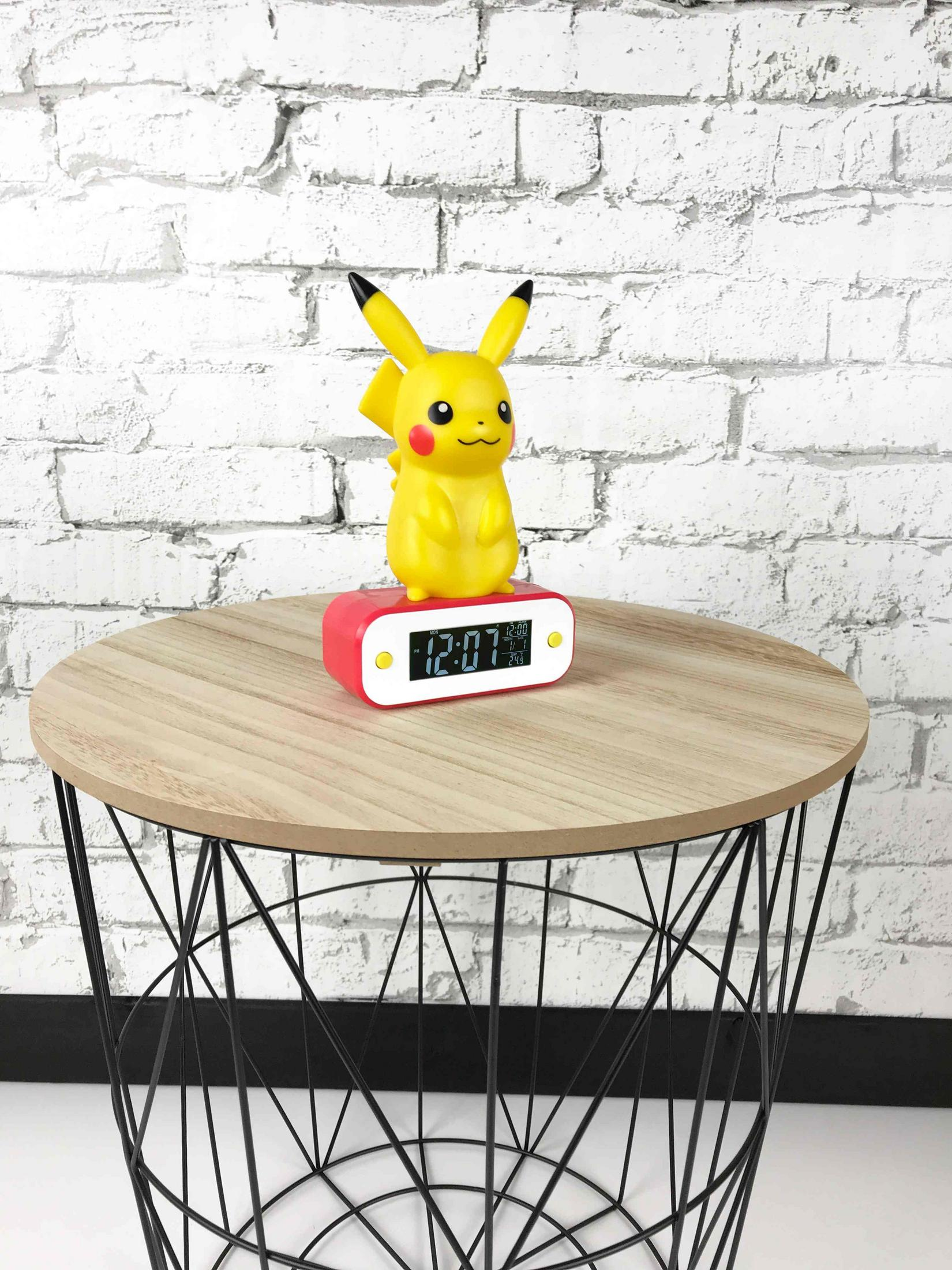 Sveglia Pikachu su tavolo di legno davanti a muro di mattoni bianchi.