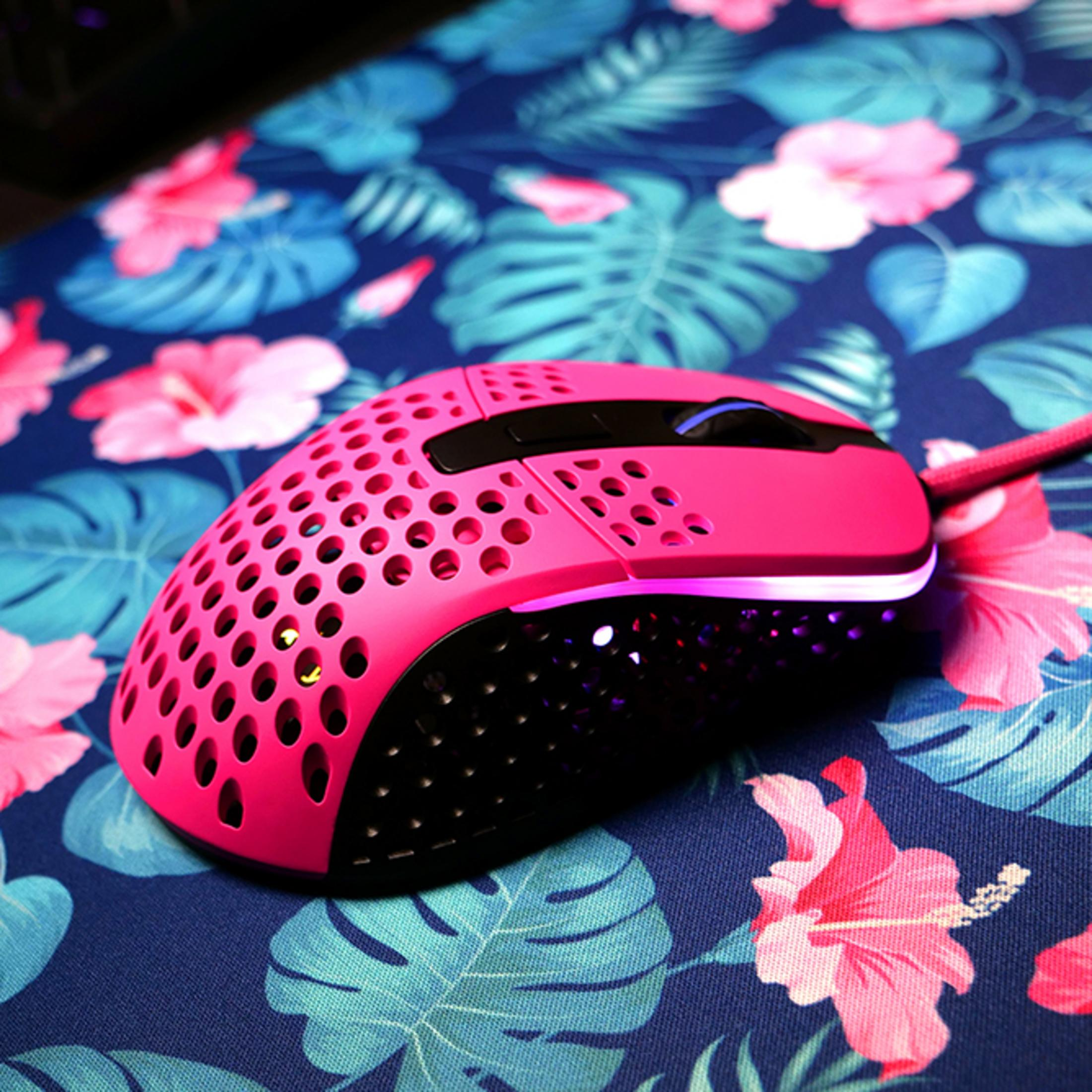 A pink gaming mouse with air vents on a tropical patterned mat.