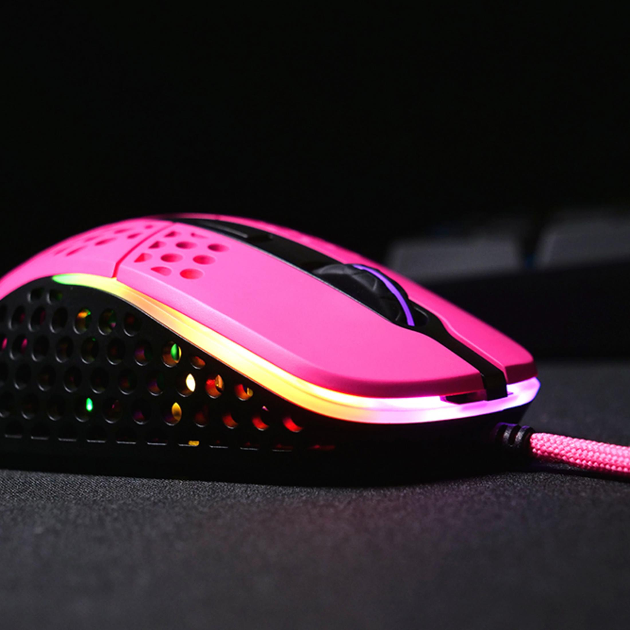 Pink gaming mouse with hole pattern and RGB lighting on black surface.
