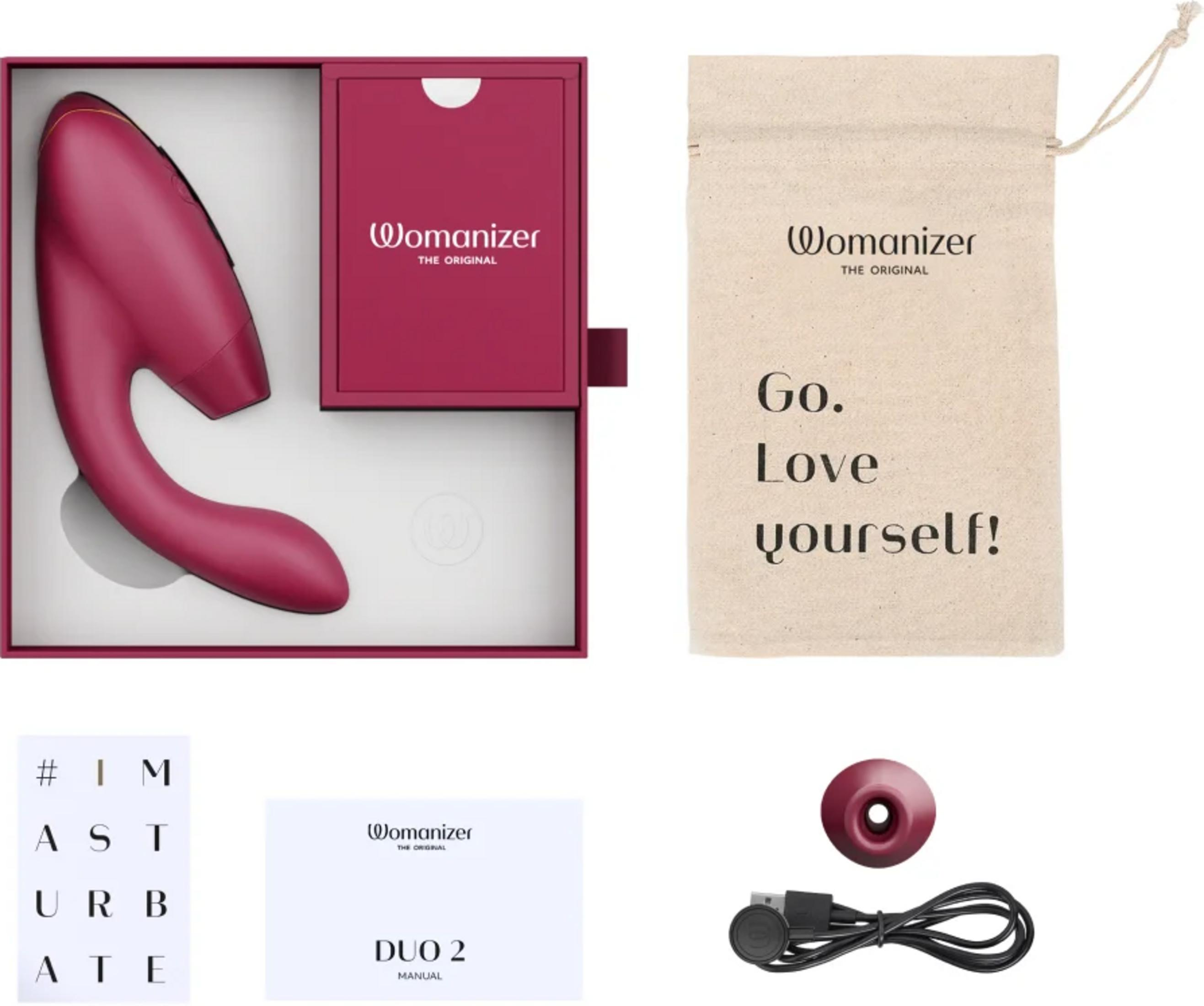 Un Womanizer rosa en una caja con bolsa, manual y cable de carga.