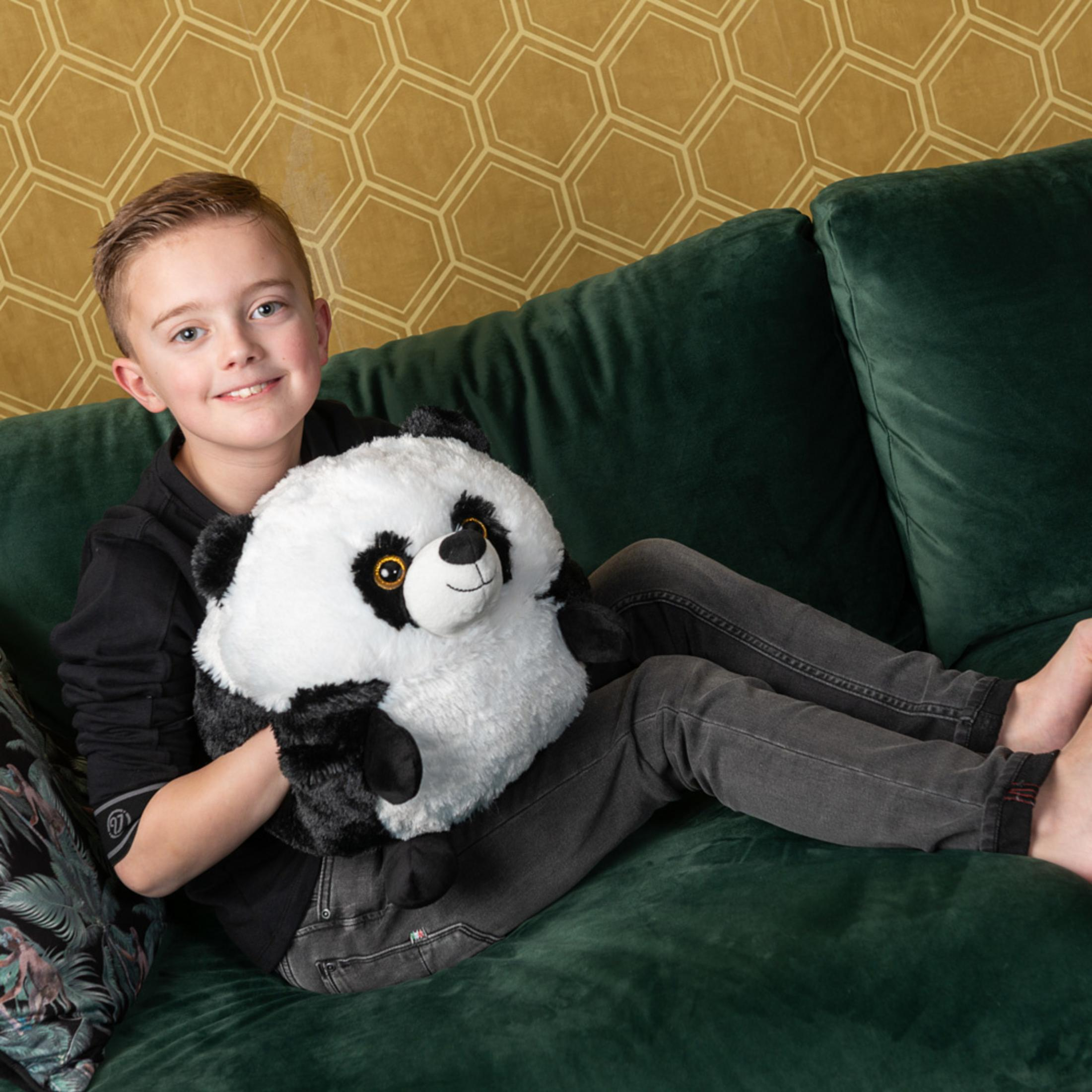 Ein Junge sitzt auf einem Sofa und hält einen Plüschpanda.