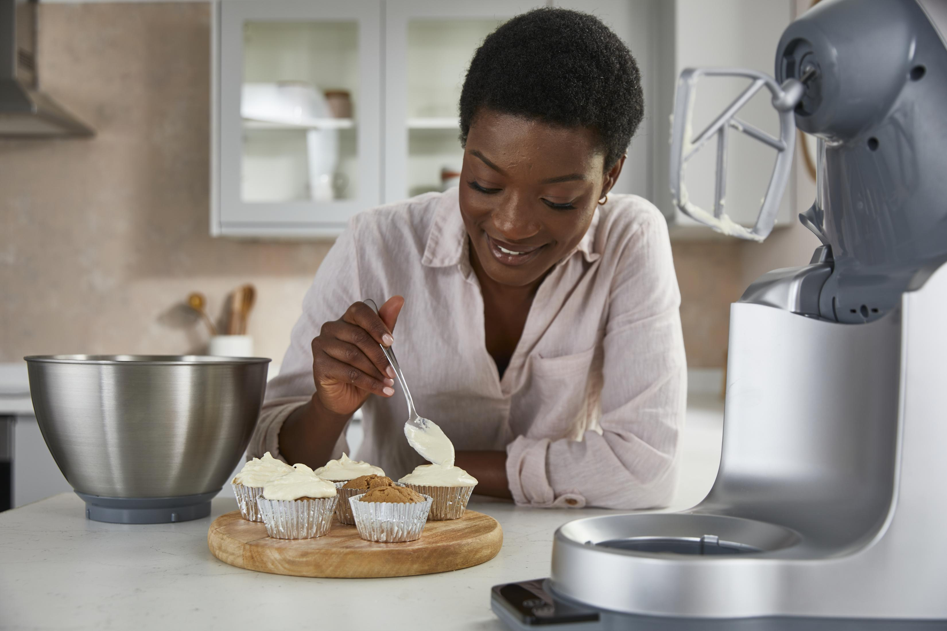 Una donna decora cupcake con glassa in una cucina.