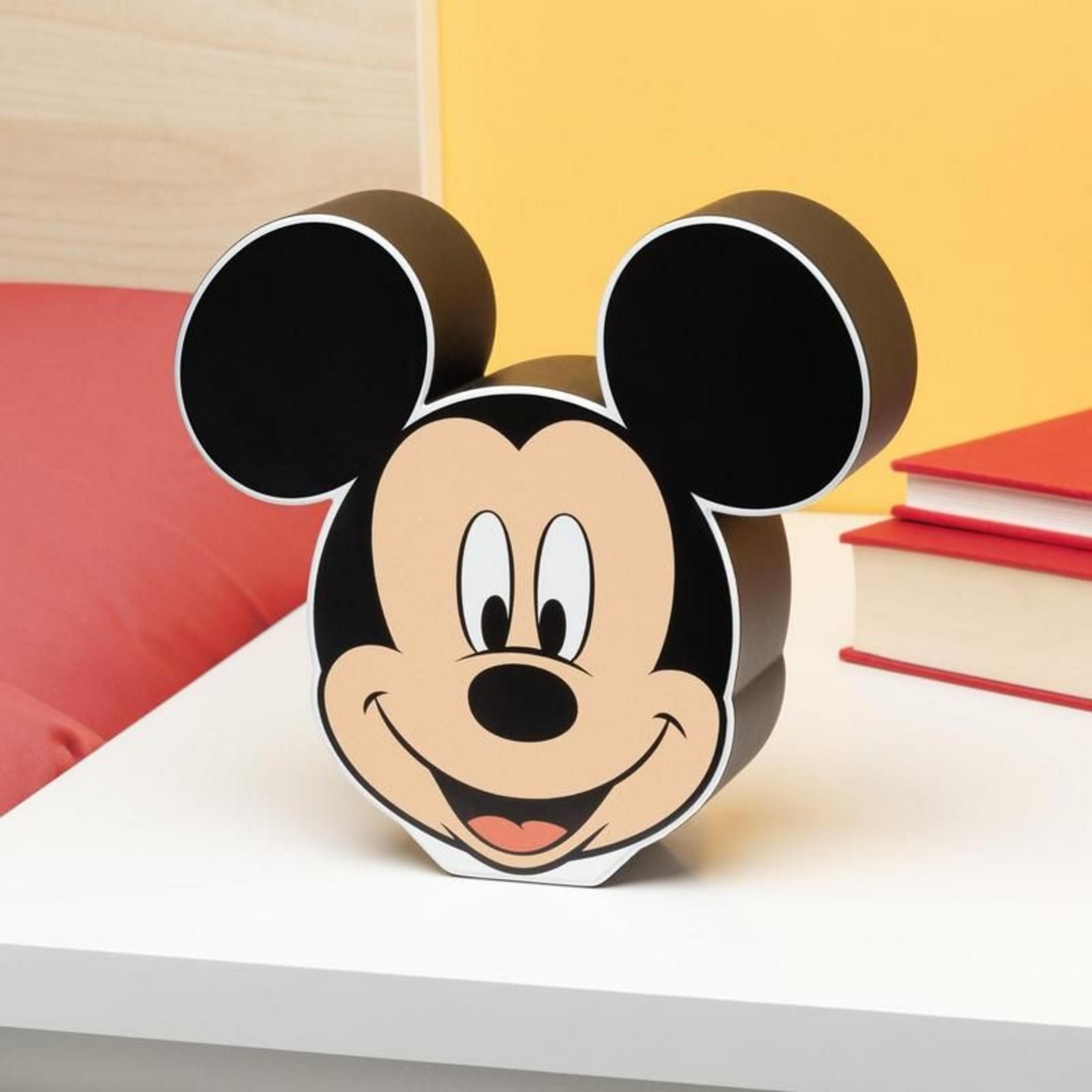 Mickey Maus Kopf auf weißem Tisch, rote und gelbe Hintergründe.