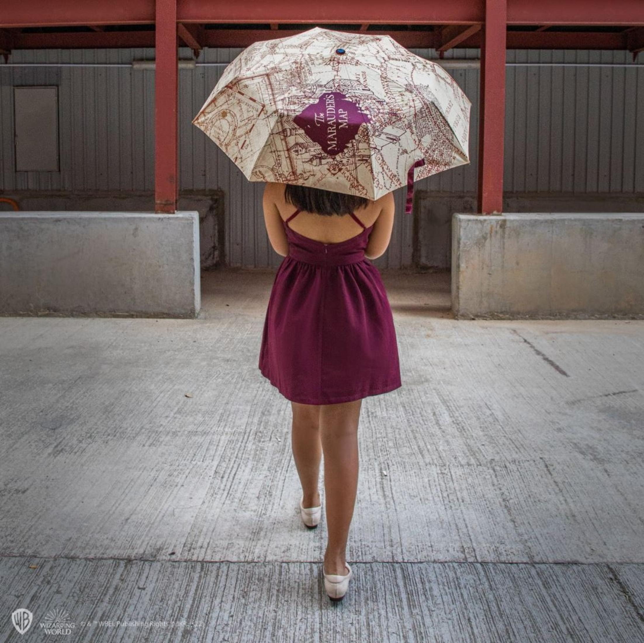 Eine Frau mit einem Regenschirm mit der Karte des Rumtreibers geht.