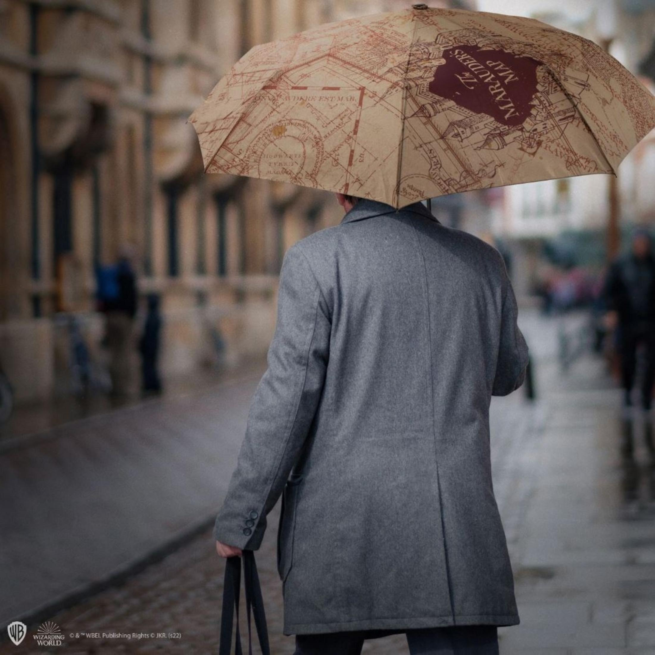 Mann mit Marauders Map Regenschirm geht durch eine Gasse.