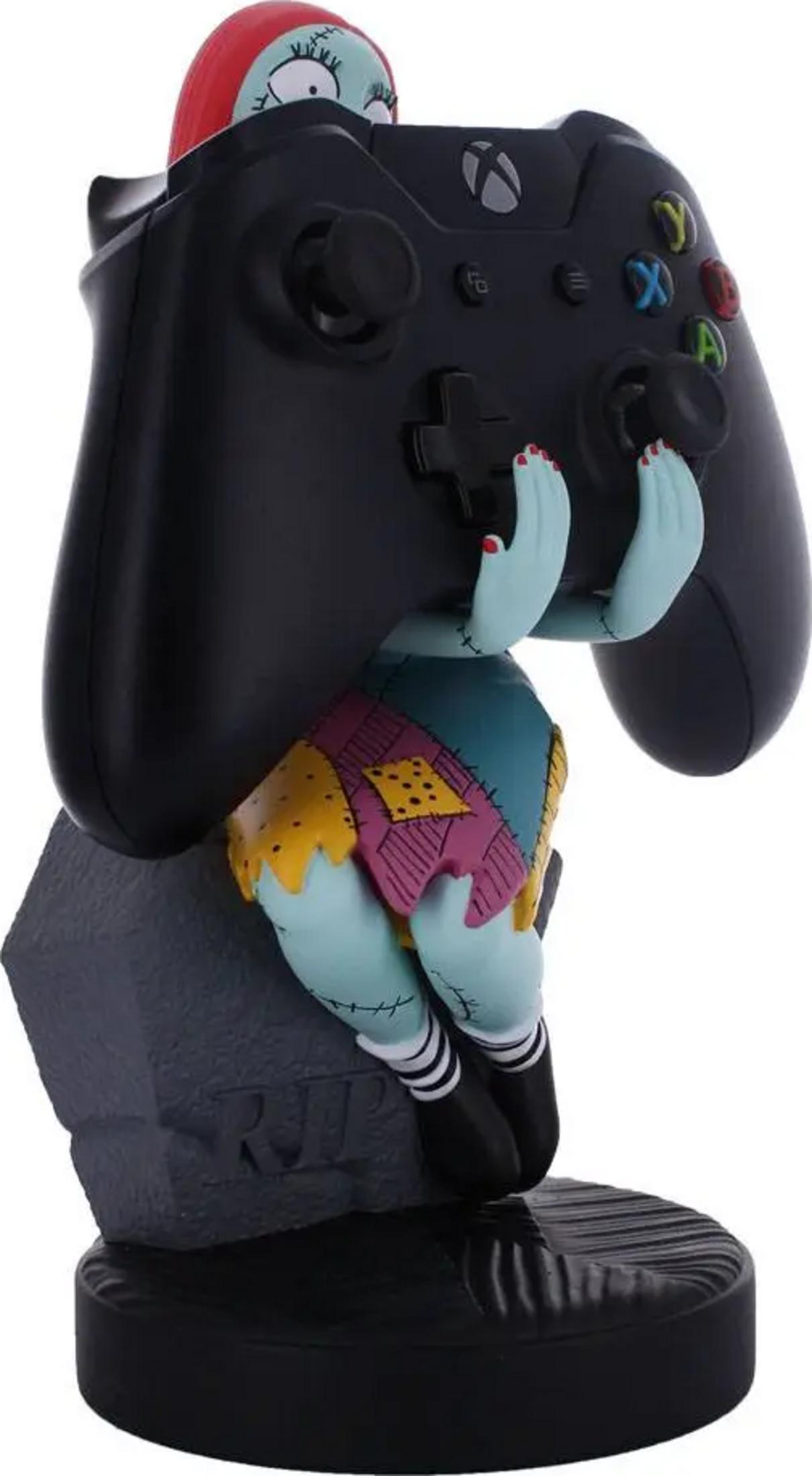 Figurka Sally trzyma czarny kontroler Xbox, siedząc na podstawie nagrobka.