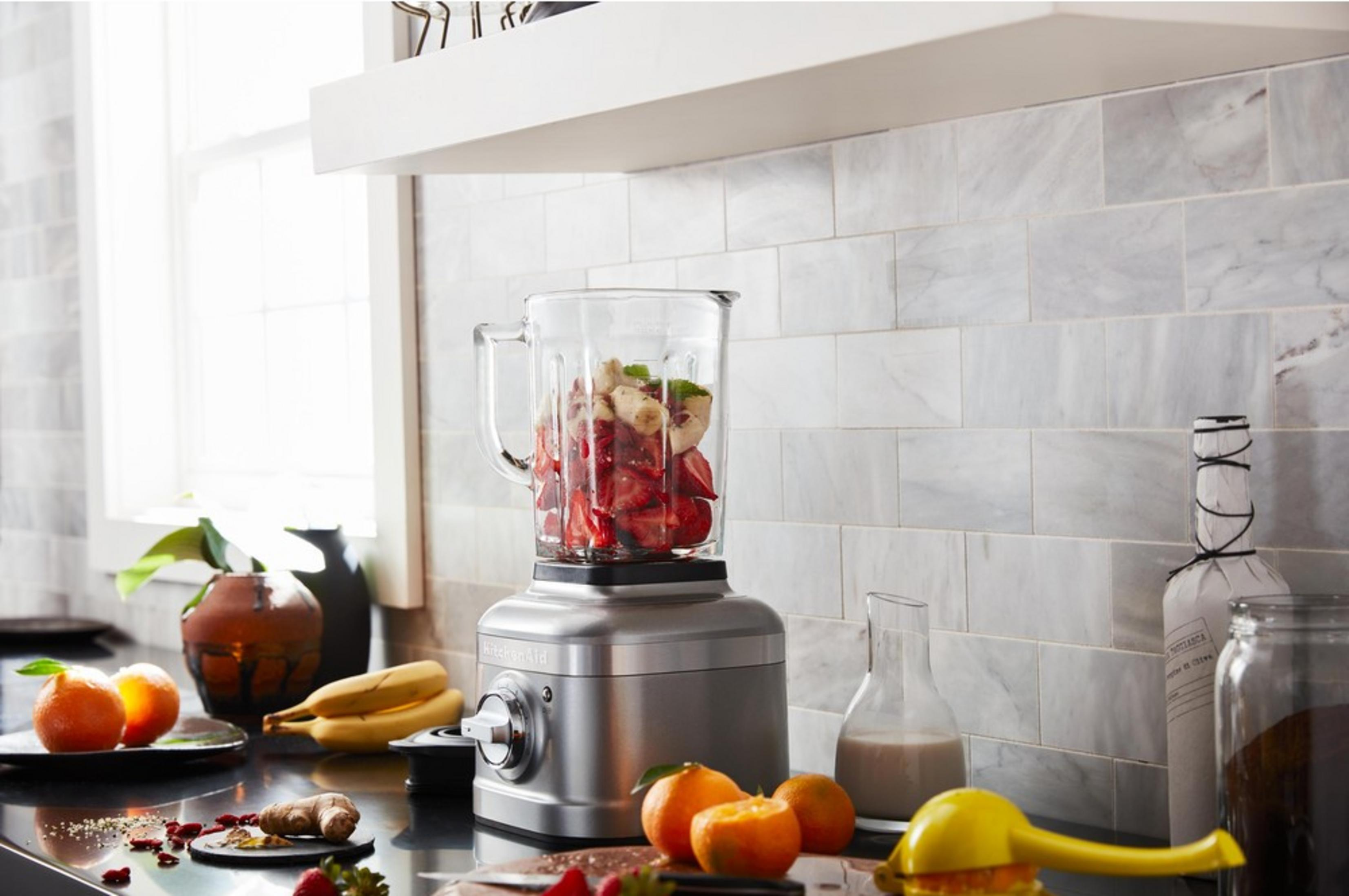 Srebrny blender wypełniony truskawkami i bananami, obok owoce.