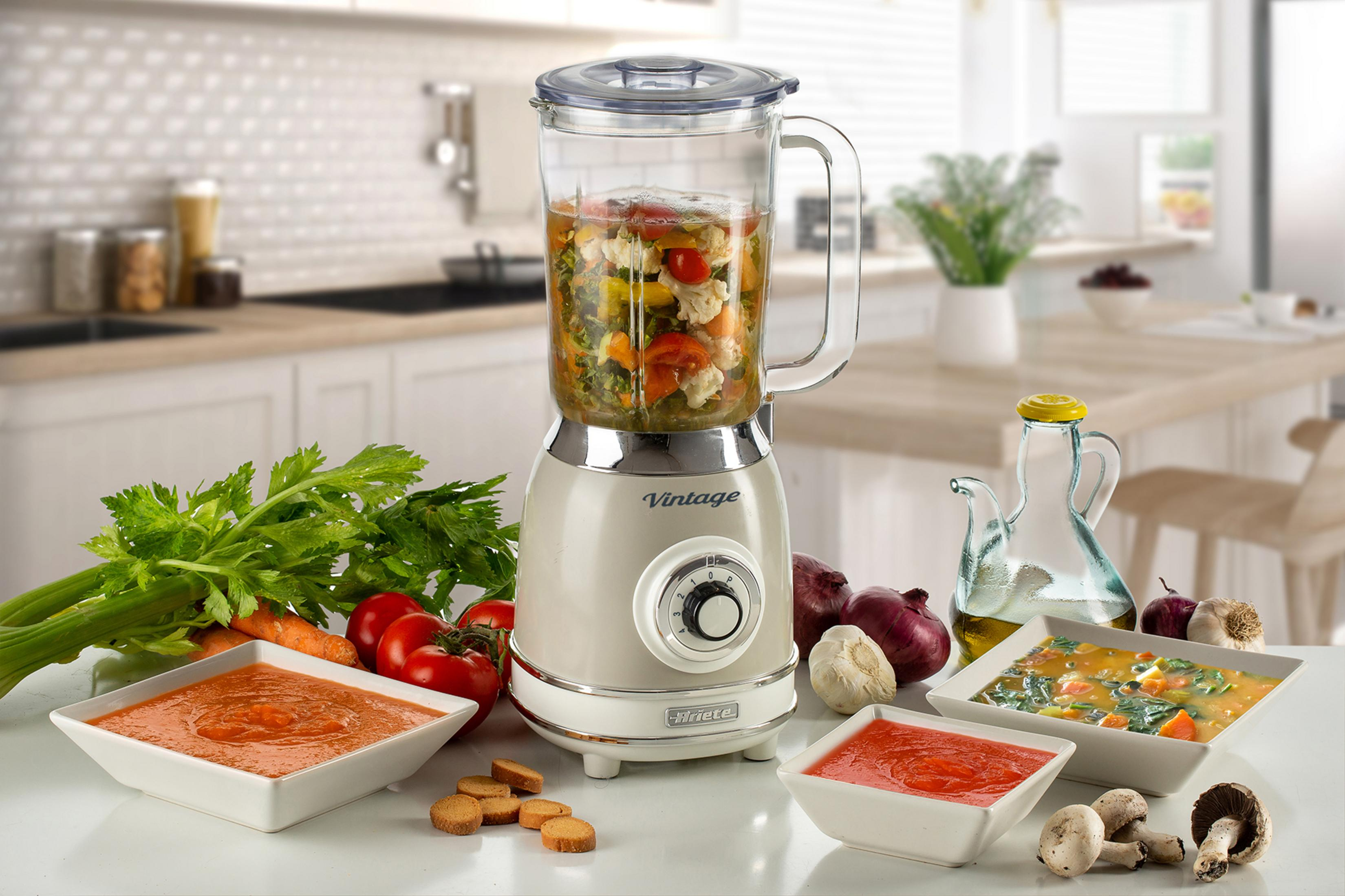 Sebzelerle dolu vintage blender, çorba kaseleri ve malzemelerin yanında duruyor.
