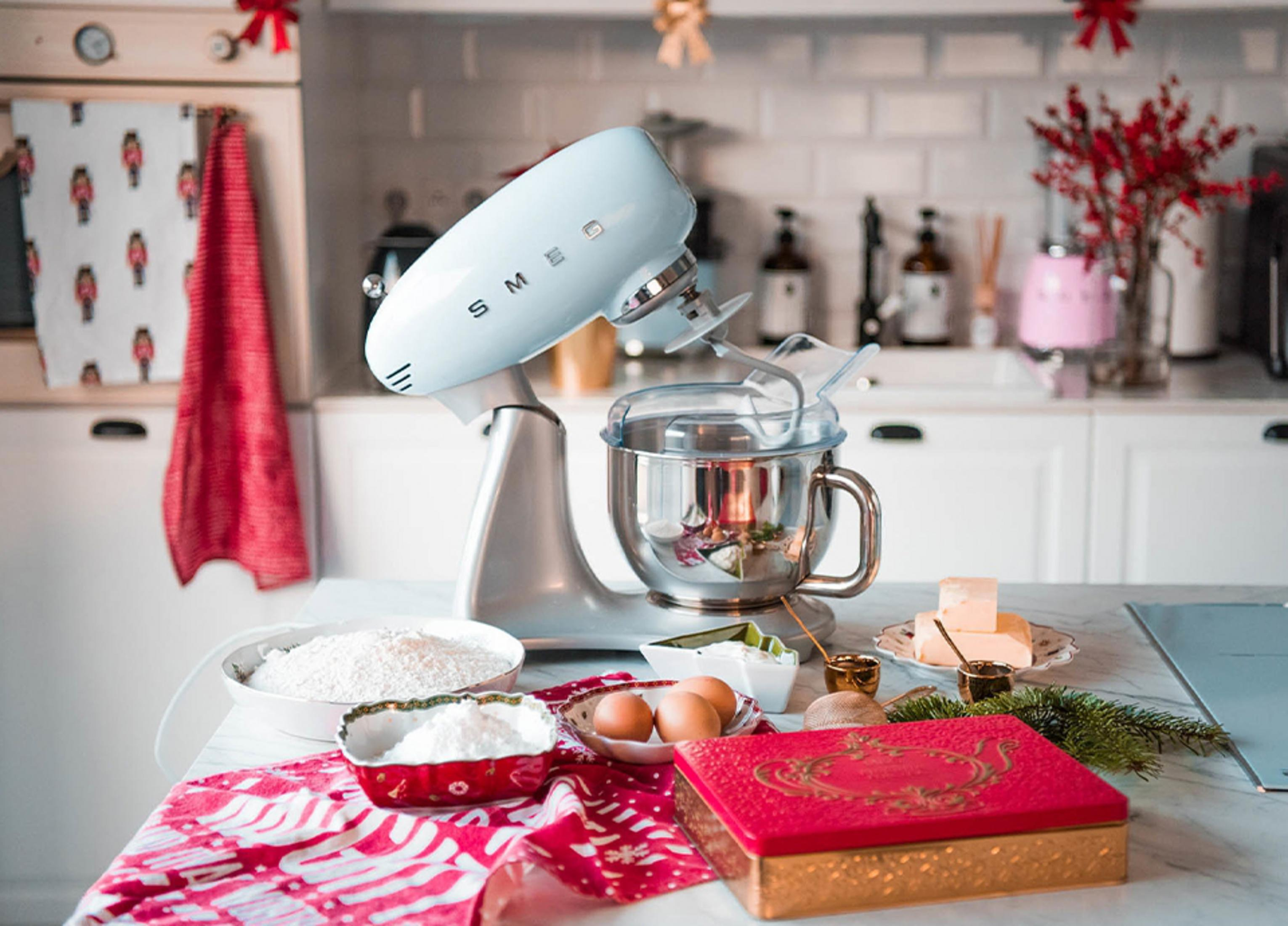 Un'impastatrice azzurra su un bancone di marmo con ingredienti per dolci.