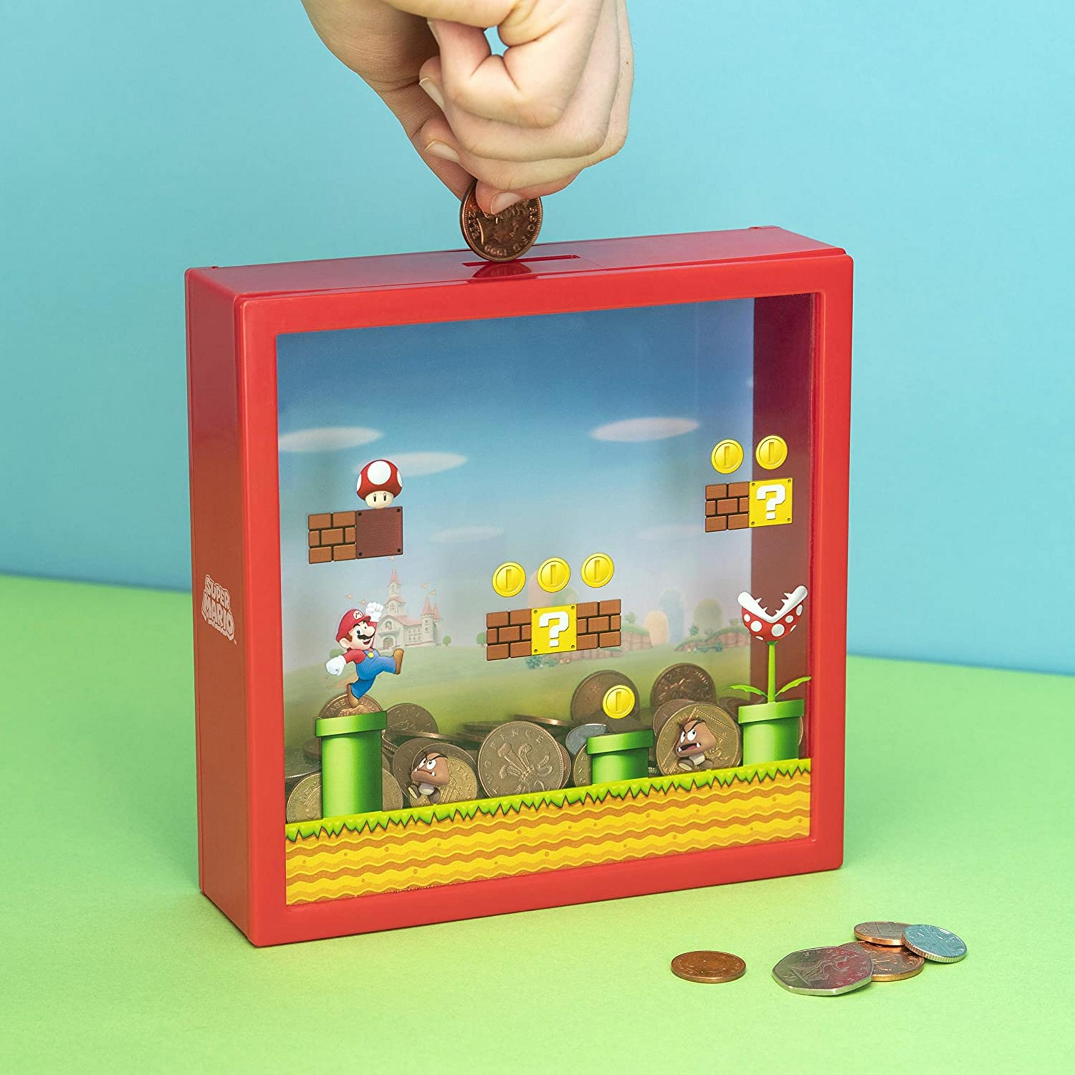 Eine Hand wirft eine Münze in einen roten Super Mario-Sparschwein.