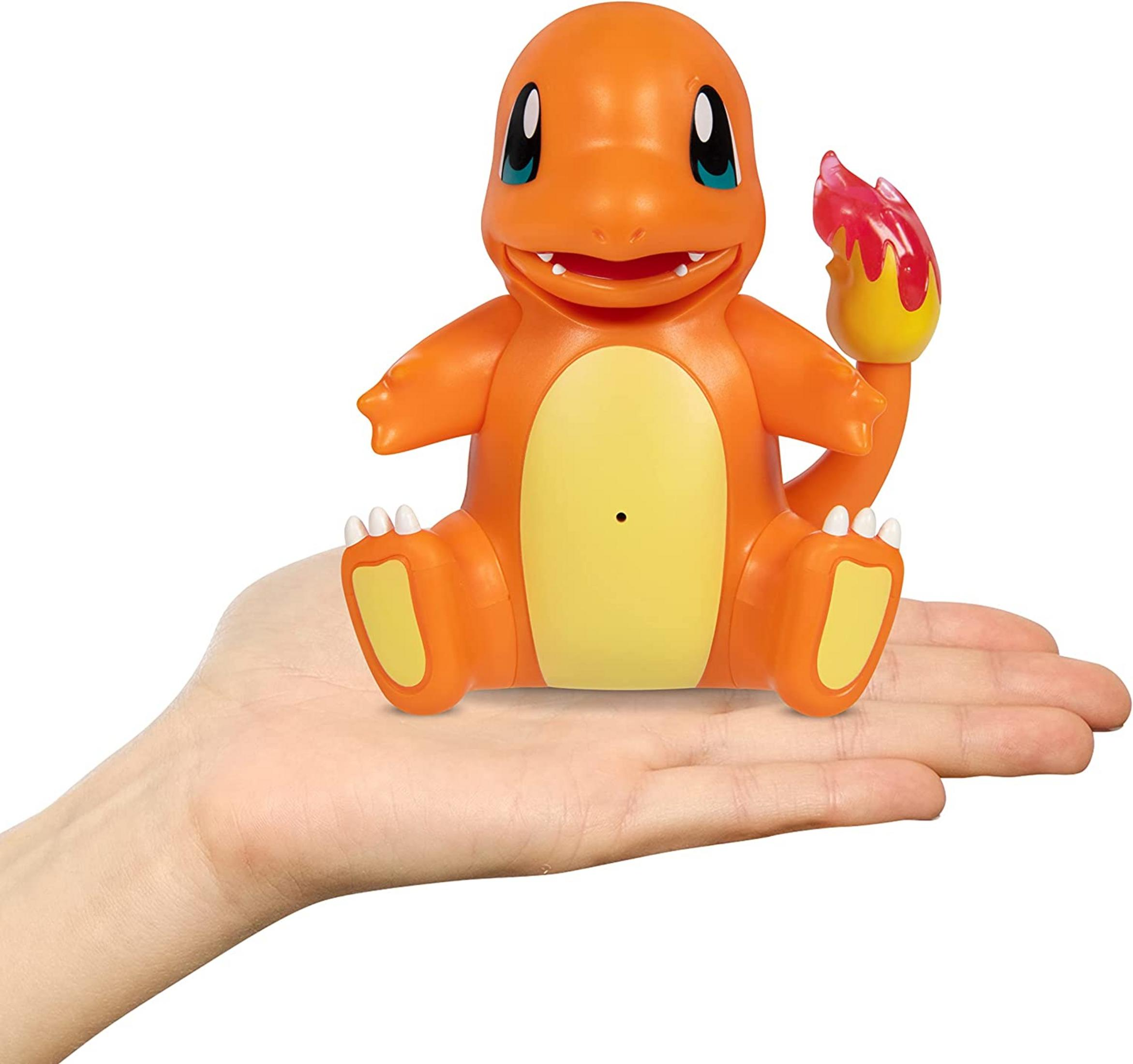 Eine orangefarbene Charmander-Figur sitzt auf einer Hand. Der Schwanz brennt.