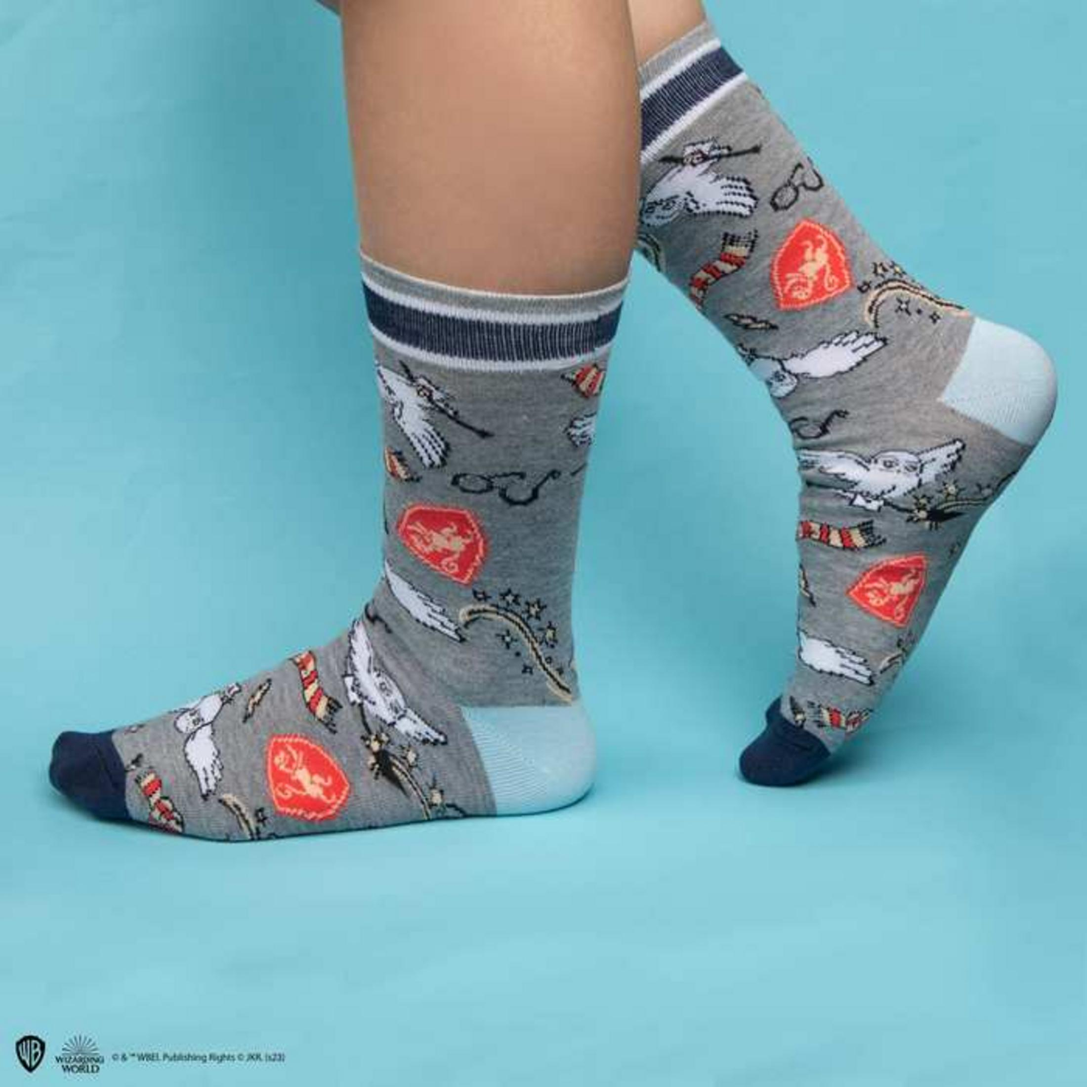 Graue Socken mit Eulen, Brillen und Wappen, getragen auf blauem Hintergrund.