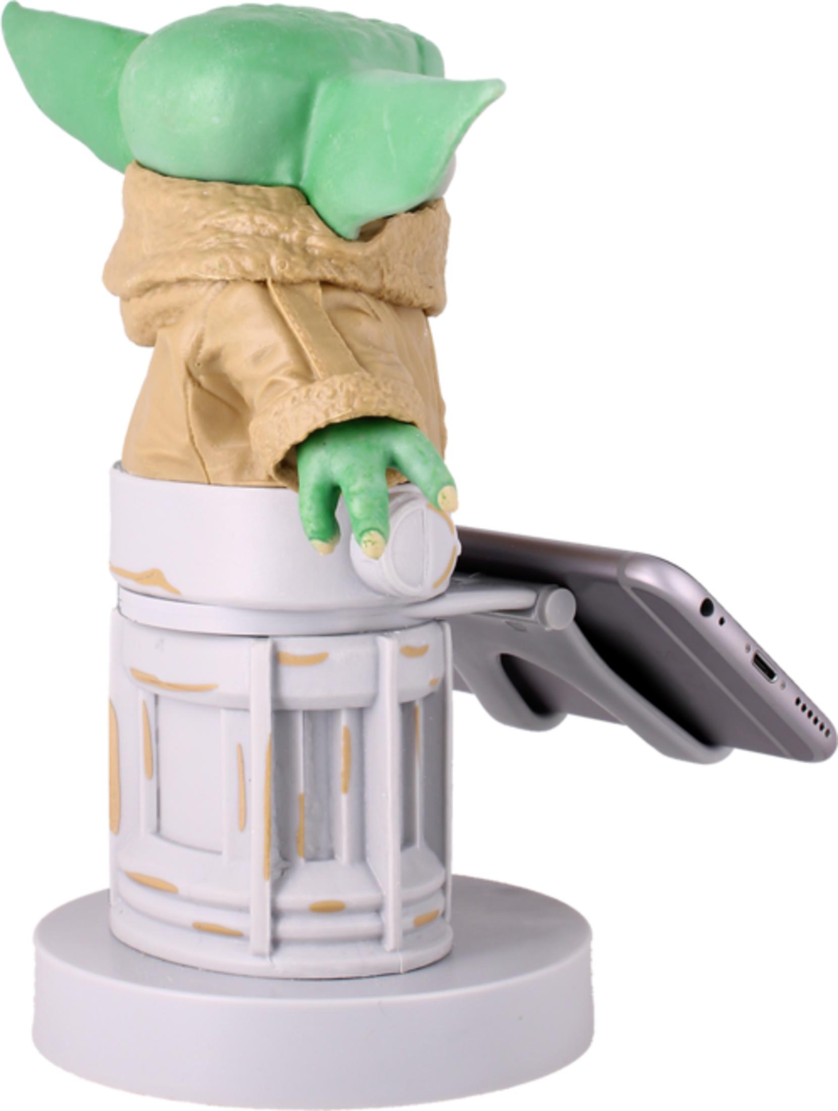 Statua di Baby Yoda con porta telefono, su base bianca.
