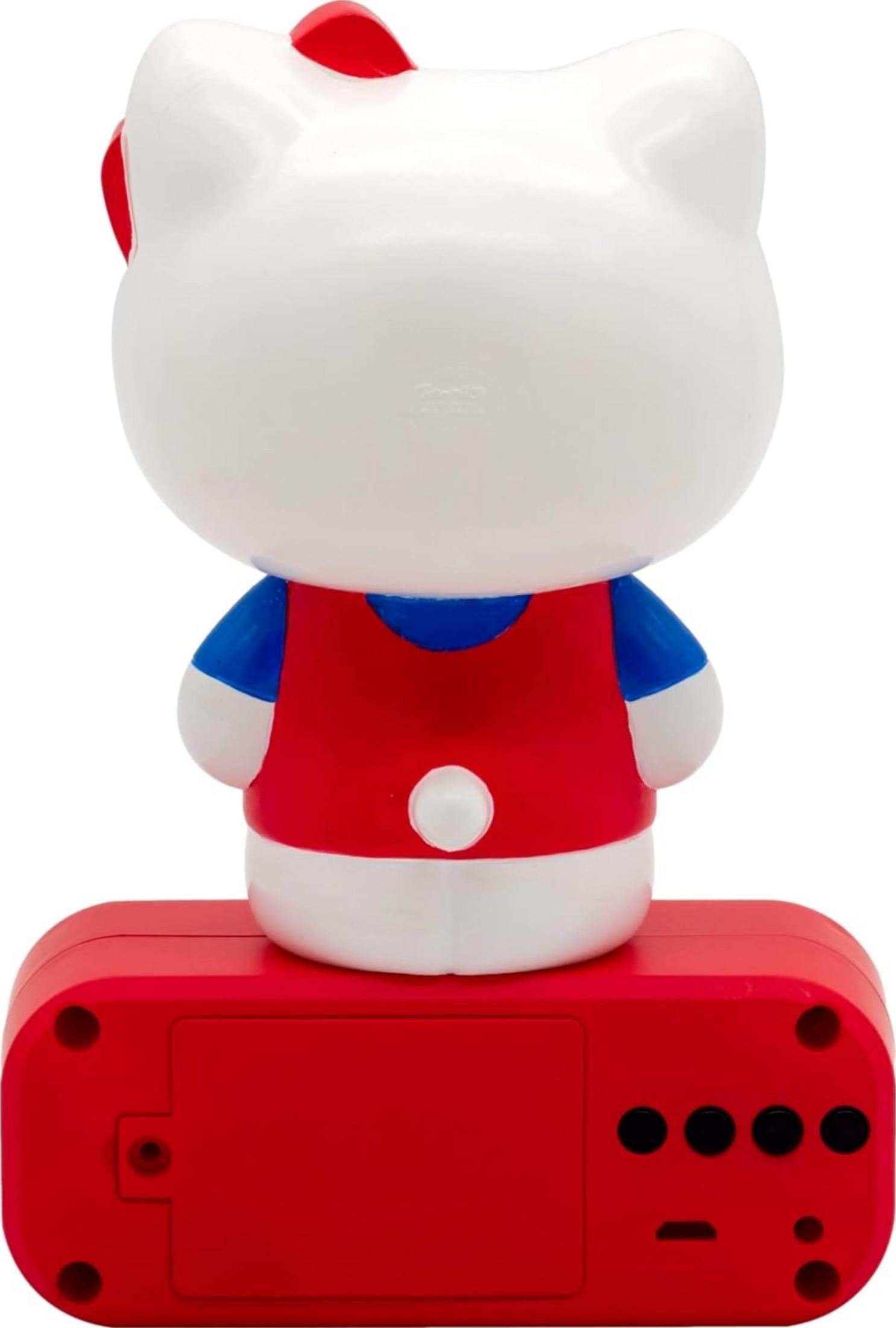 Widok z tyłu białej postaci Hello Kitty w czerwonej sukience z niebieskimi rękawami na czerwonej podstawie.