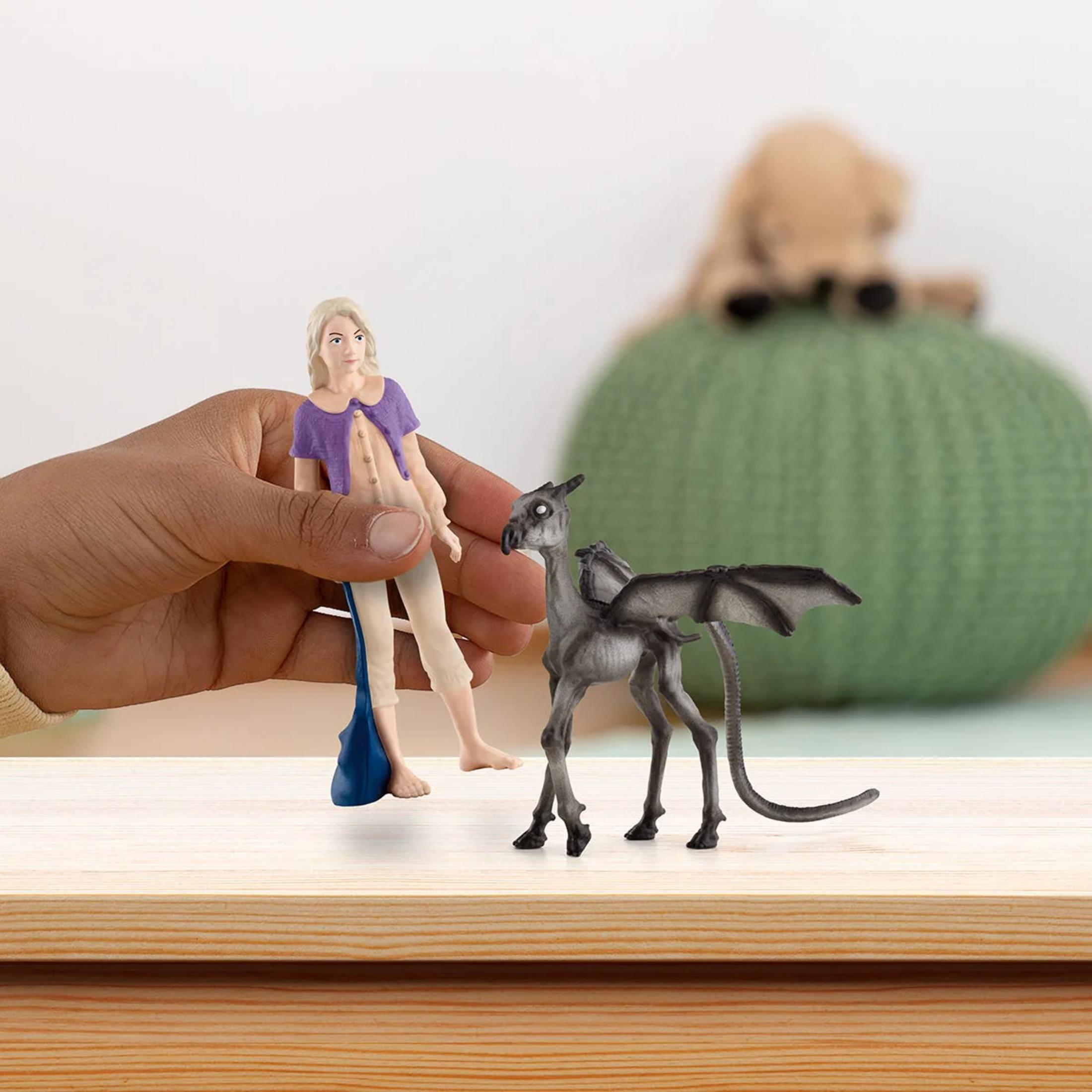 Una mano tiene una figura accanto a una figura di drago grigio con ali.
