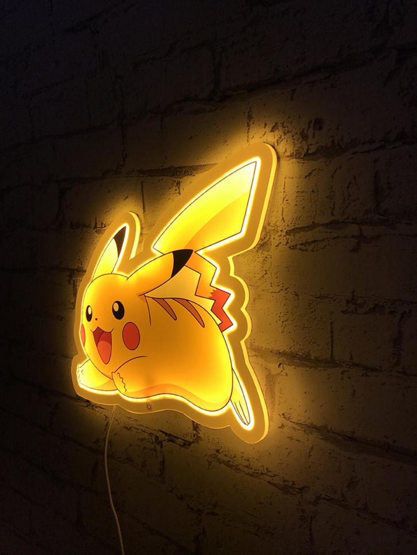 Eine leuchtende Pikachu-Lampe hängt an einer Ziegelwand.