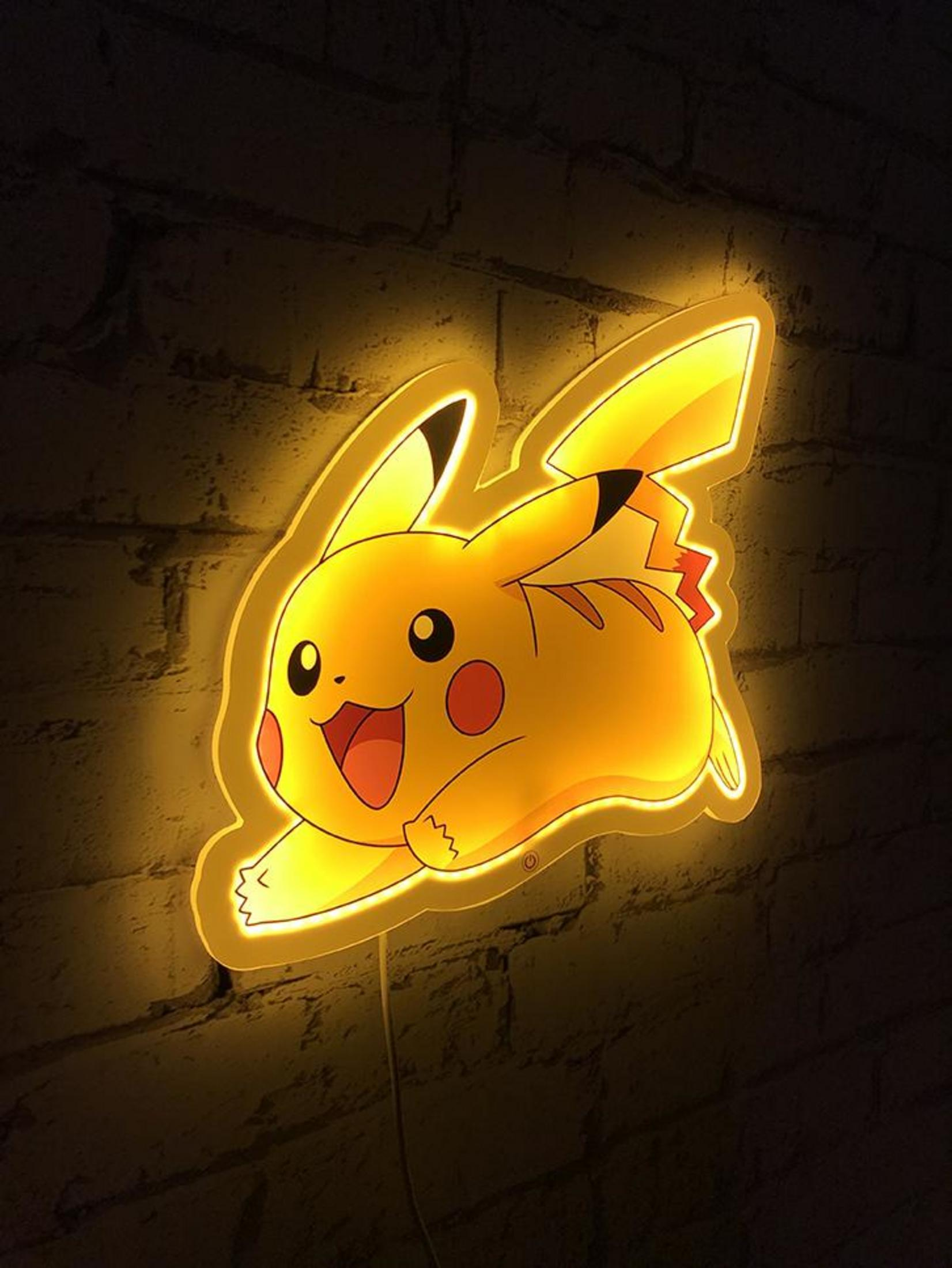 Gelbes Pikachu-Neonlicht an einer Ziegelwand, das im Dunkeln leuchtet.