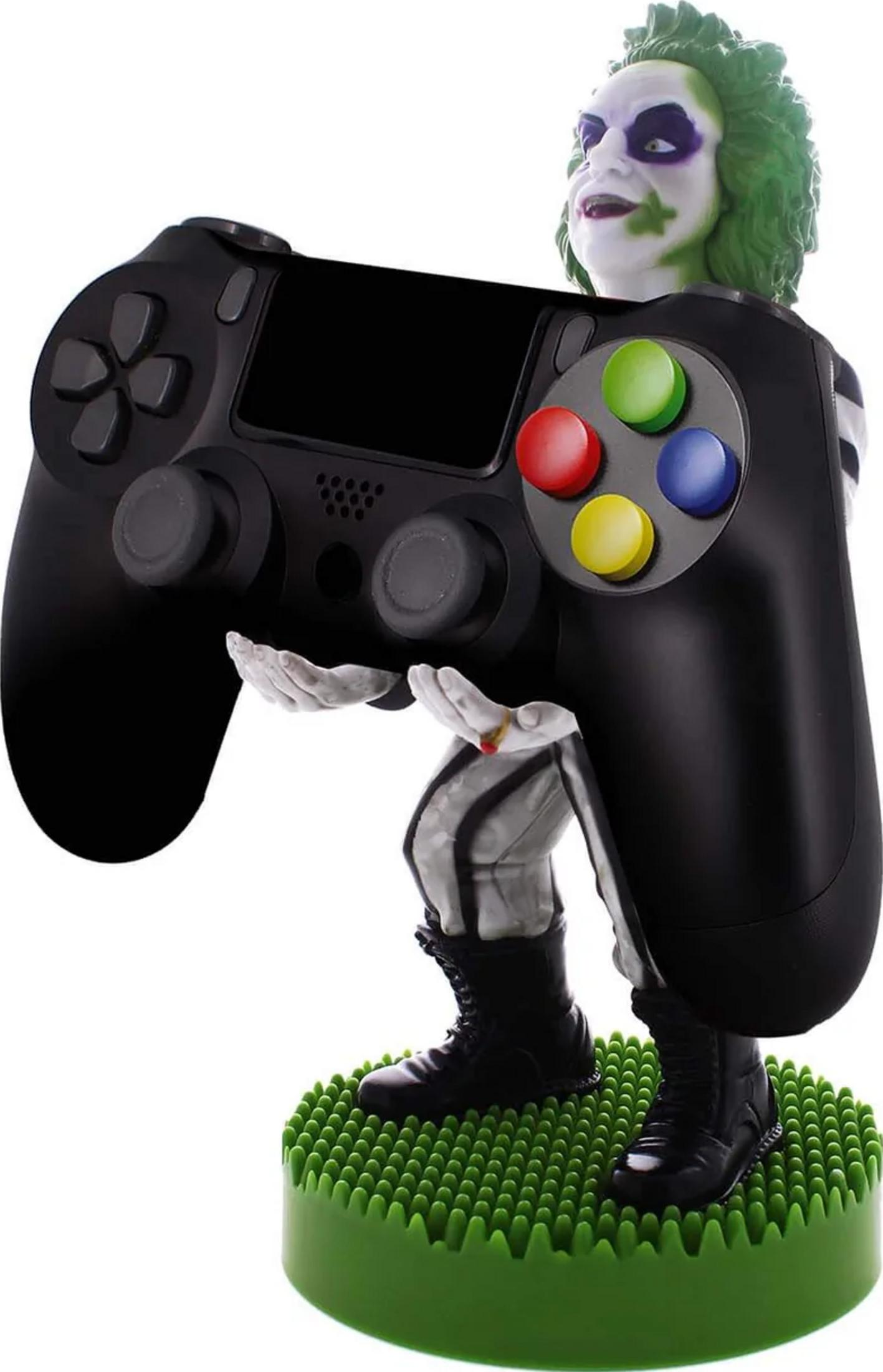 Eine Figur mit Joker-ähnlichem Make-up hält einen schwarzen Controller auf einer grünen Basis.