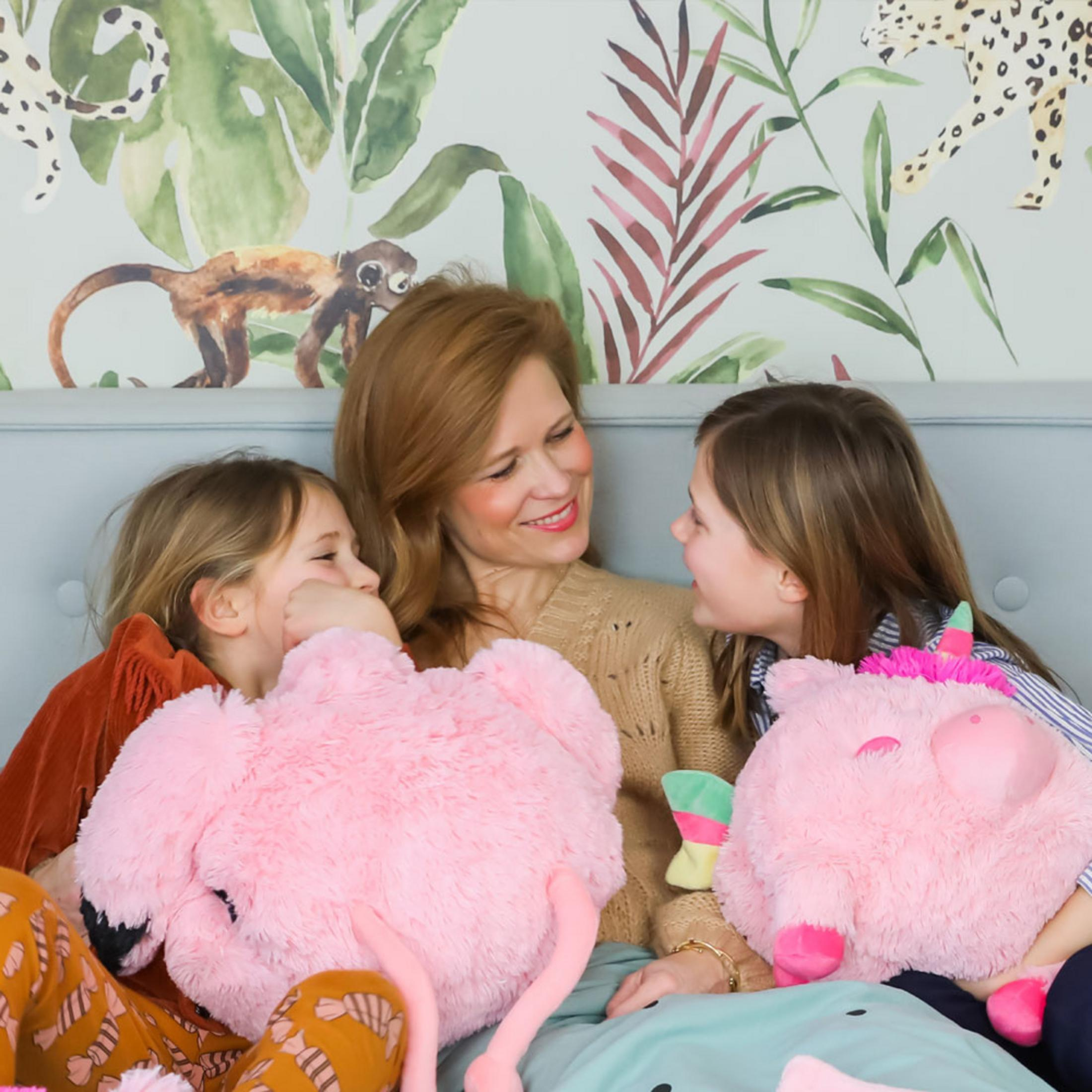 Eine Frau und zwei Mädchen kuscheln mit großen Plüschtieren im Dschungel-Ambiente.