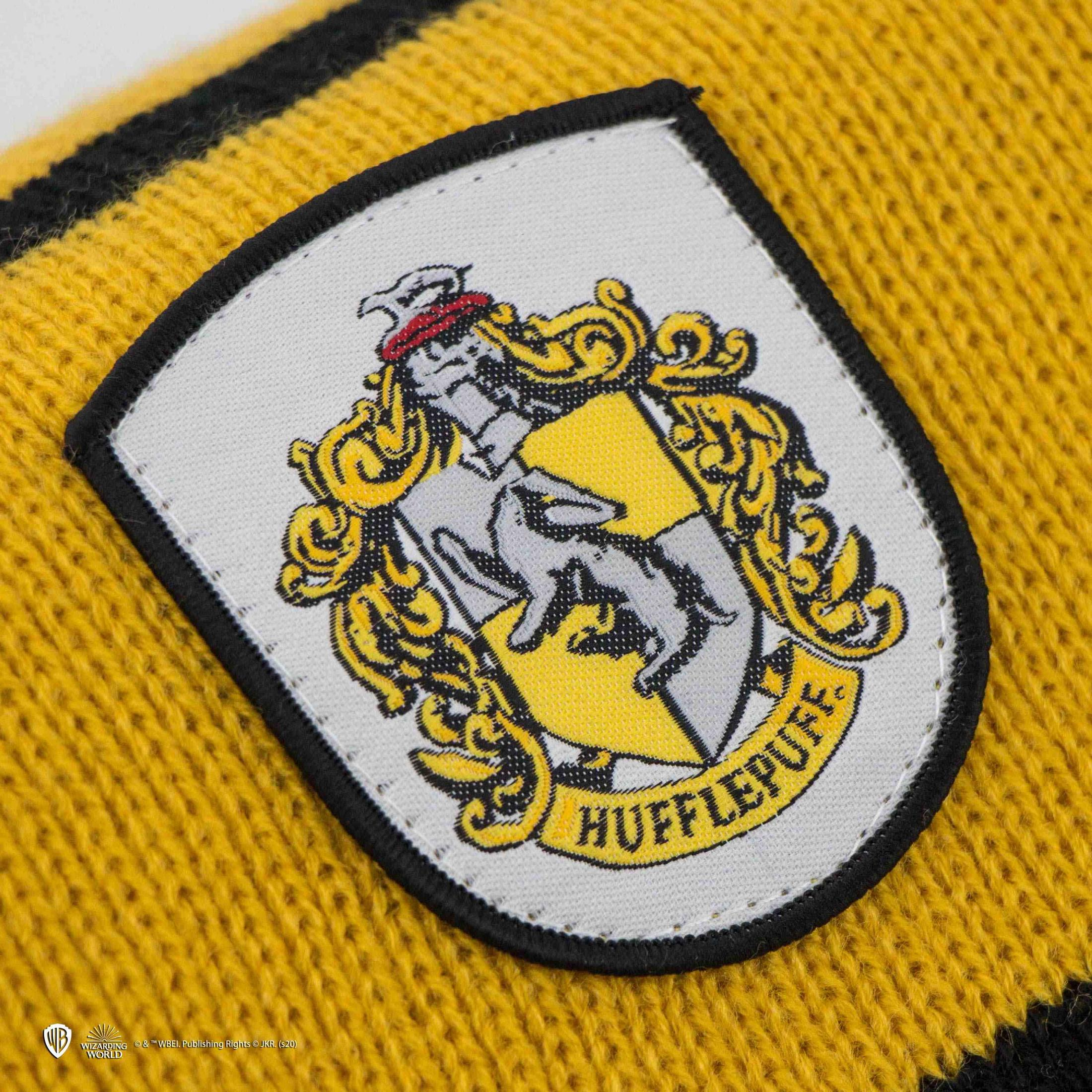 Ein gelber Pullover mit einem Hufflepuff-Wappen und schwarzen Streifen.