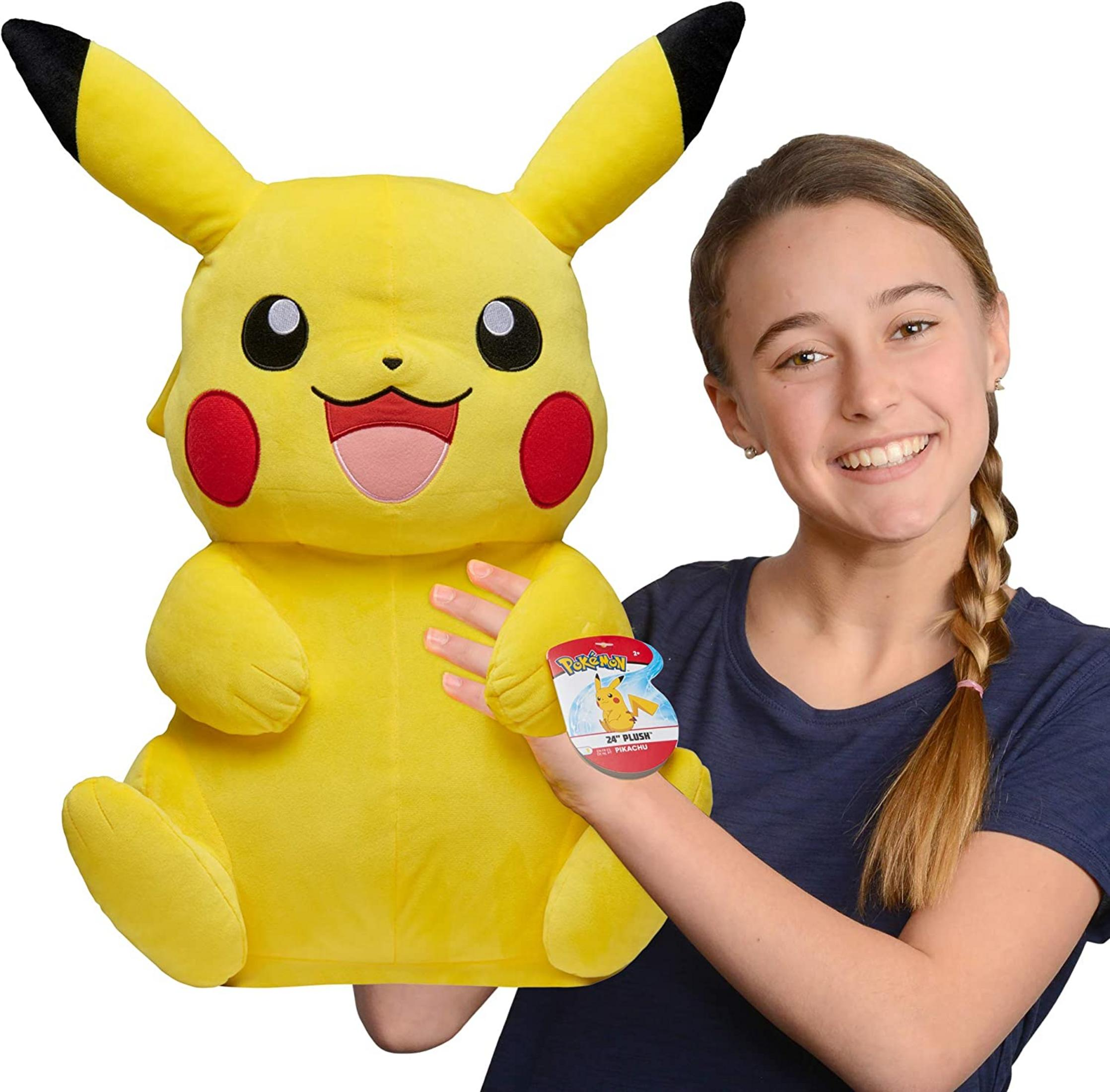 Ein lächelndes Mädchen hält ein großes, gelbes Pikachu-Plüschtier mit schwarzen Ohrenspitzen.