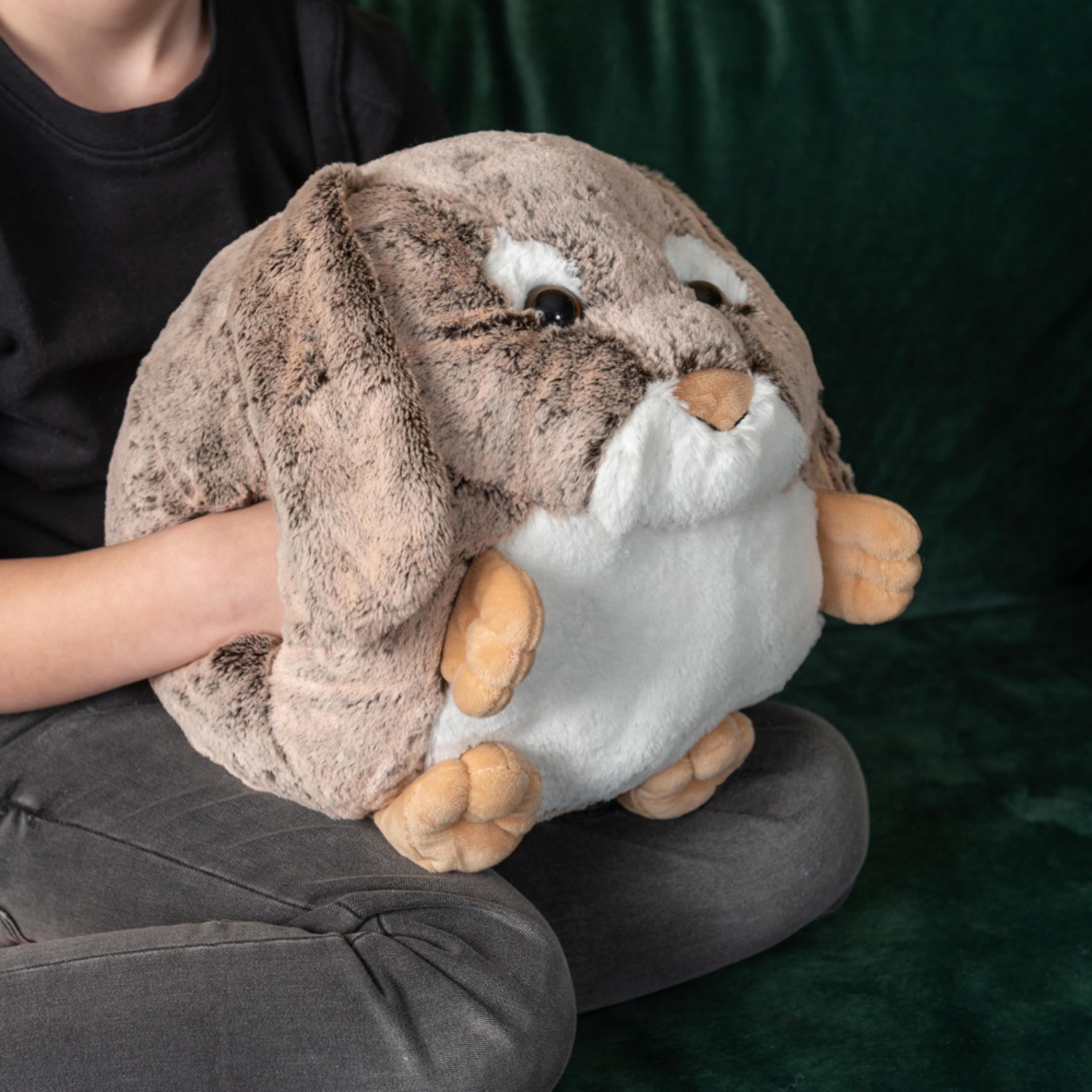 Ein flauschiges braunes Kaninchen-Kuscheltier wird von einem Kind gehalten, das dunkle Jeans trägt.