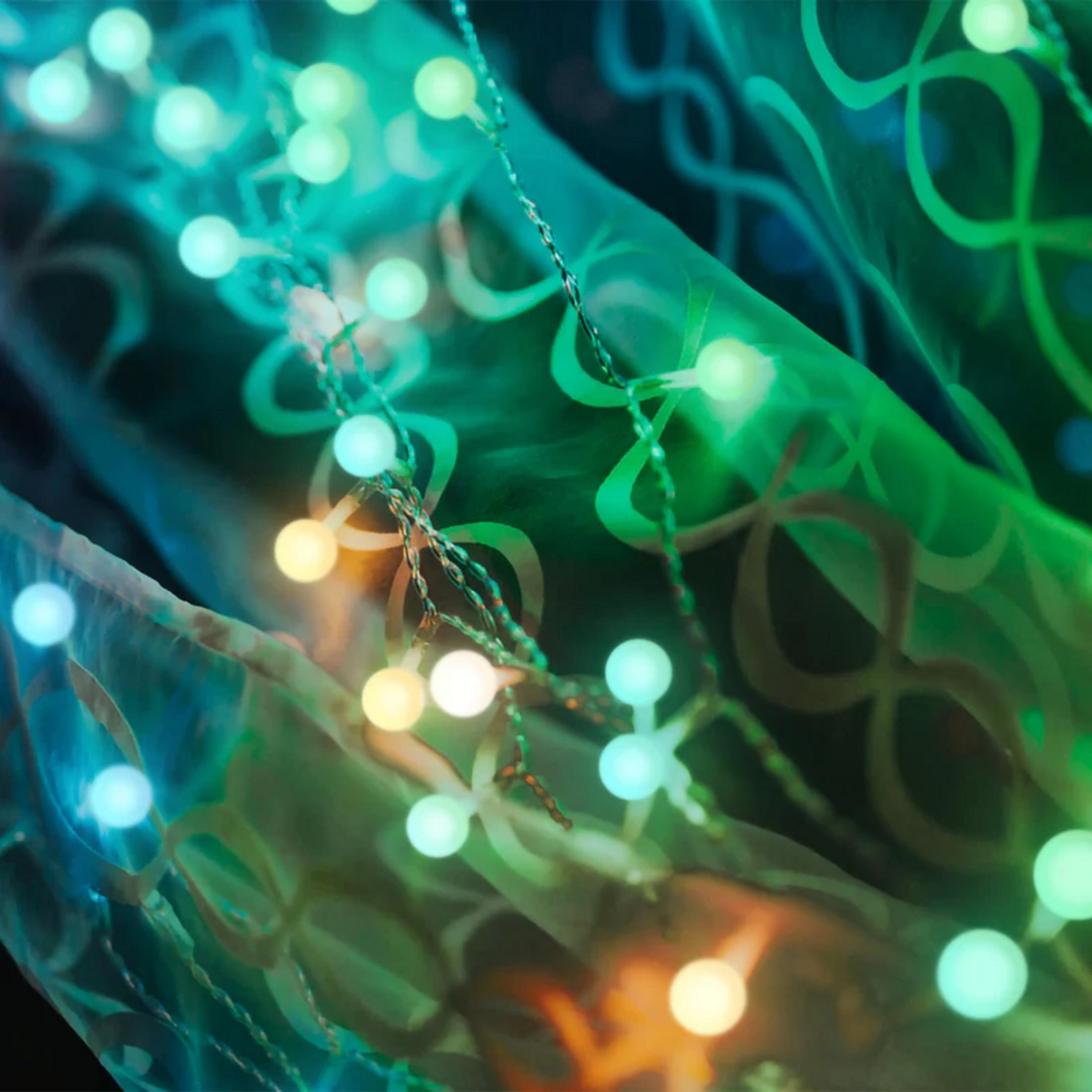 Sznur świateł z zielonymi i niebieskimi światłami na tkaninie z wzorami.