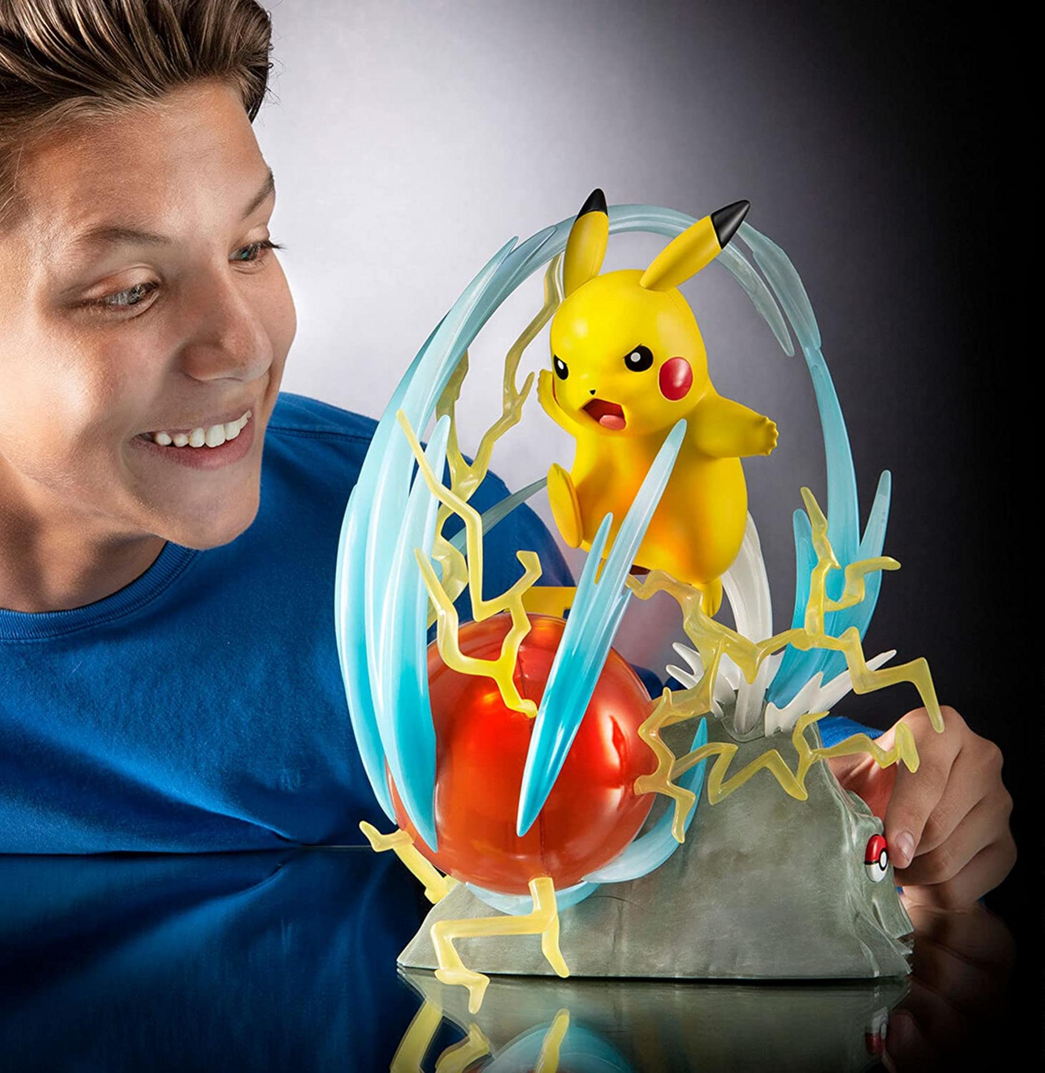 Ein Junge betrachtet eine Pikachu-Figur mit Blitzeffekten und einer roten Kugel.