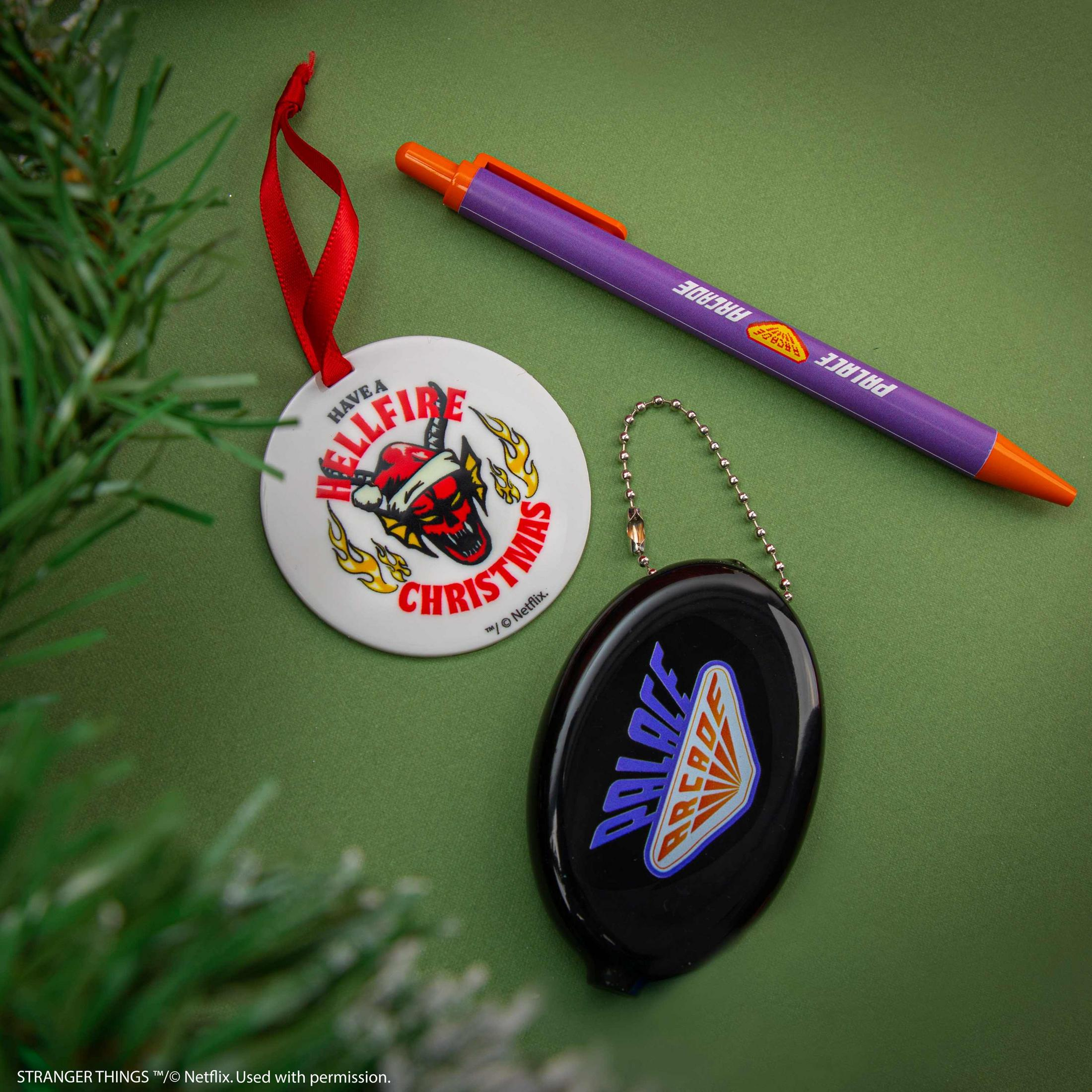 Ornement de Noël avec tête de diable, stylo et porte-clés sur fond vert.