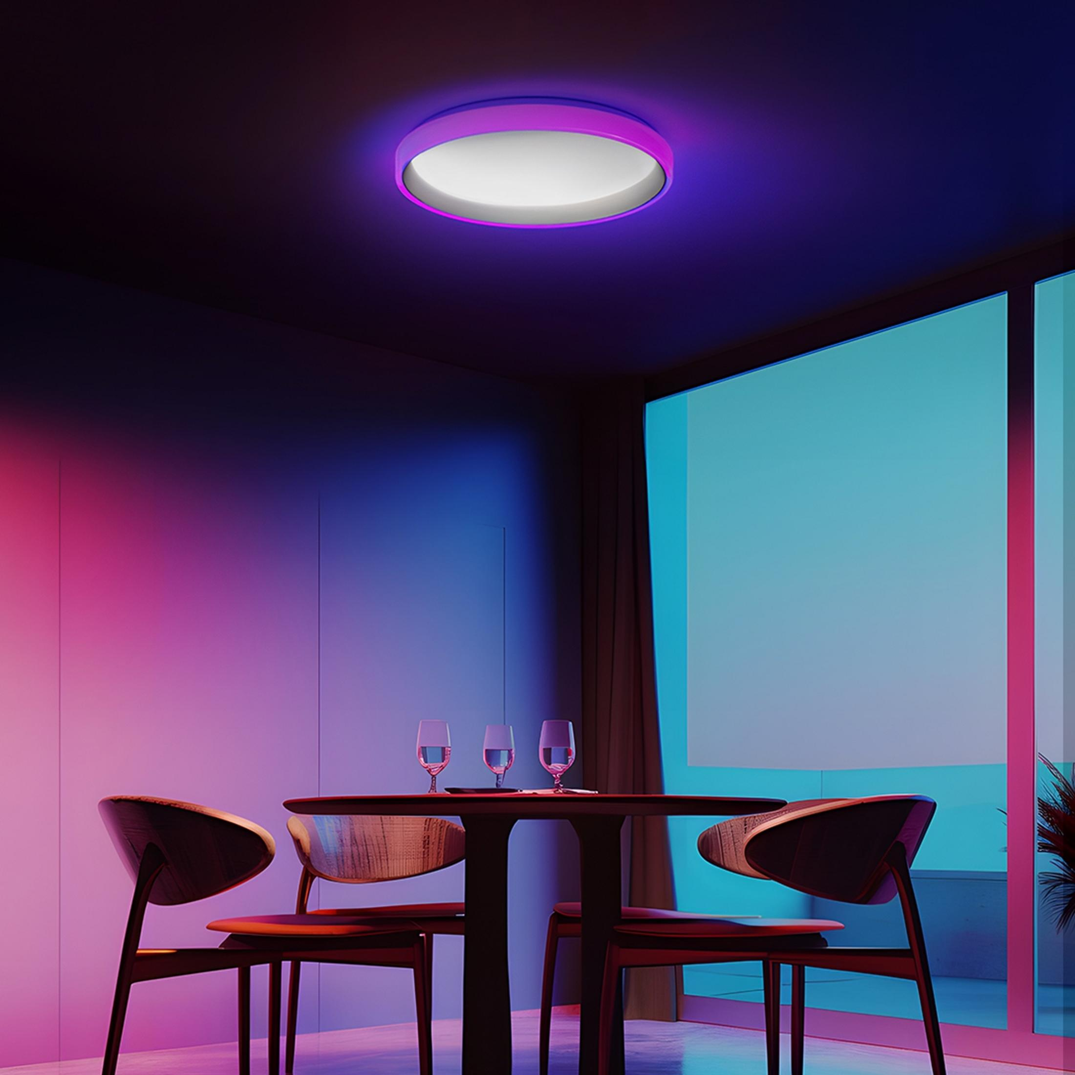 Okrągły stół z czterema krzesłami, oświetlony fioletowo-niebieskim światłem sufitowym.