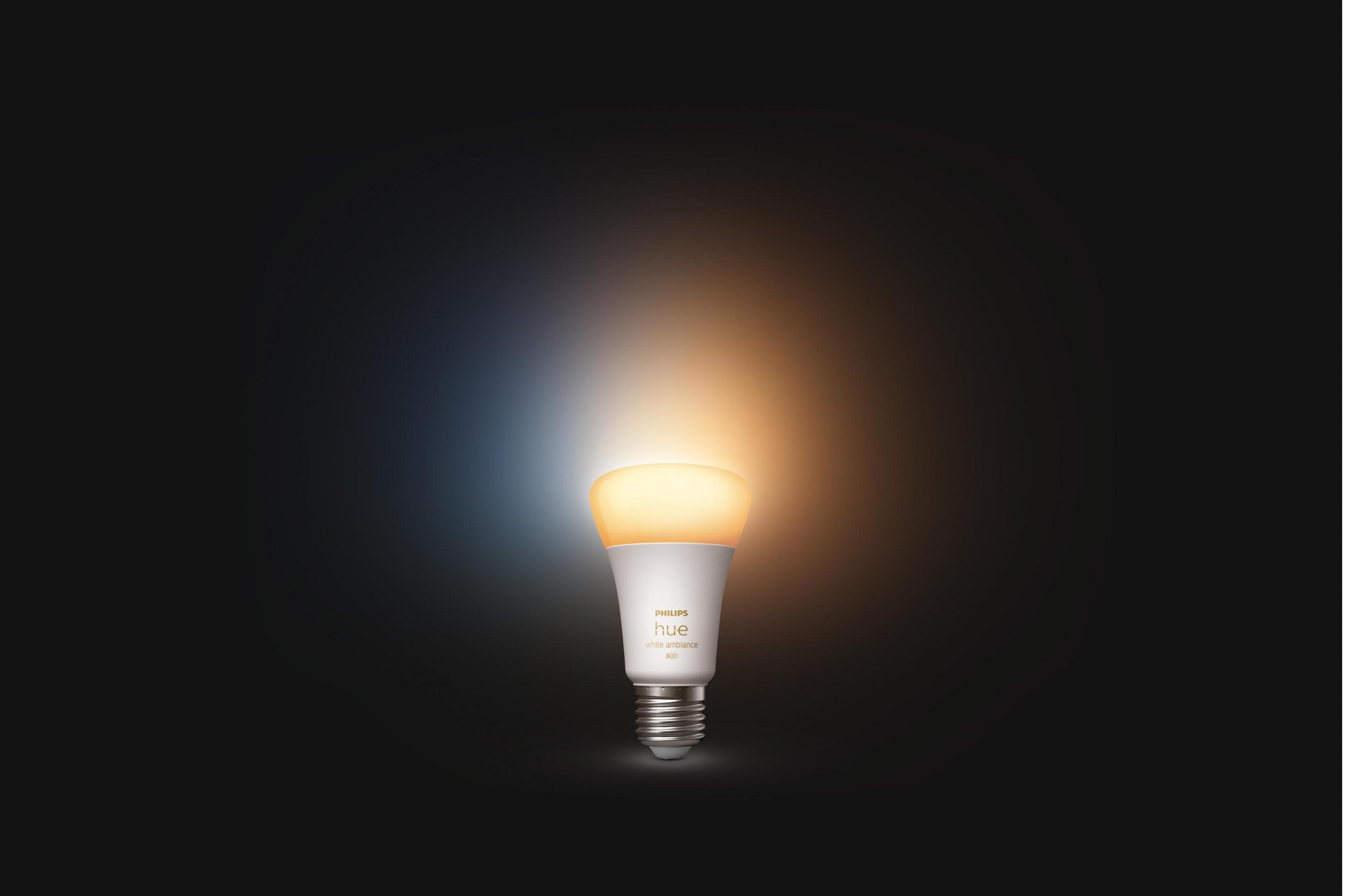 Żarówka Philips Hue świeci na ciepło biało i zimno biało na ciemnym tle.