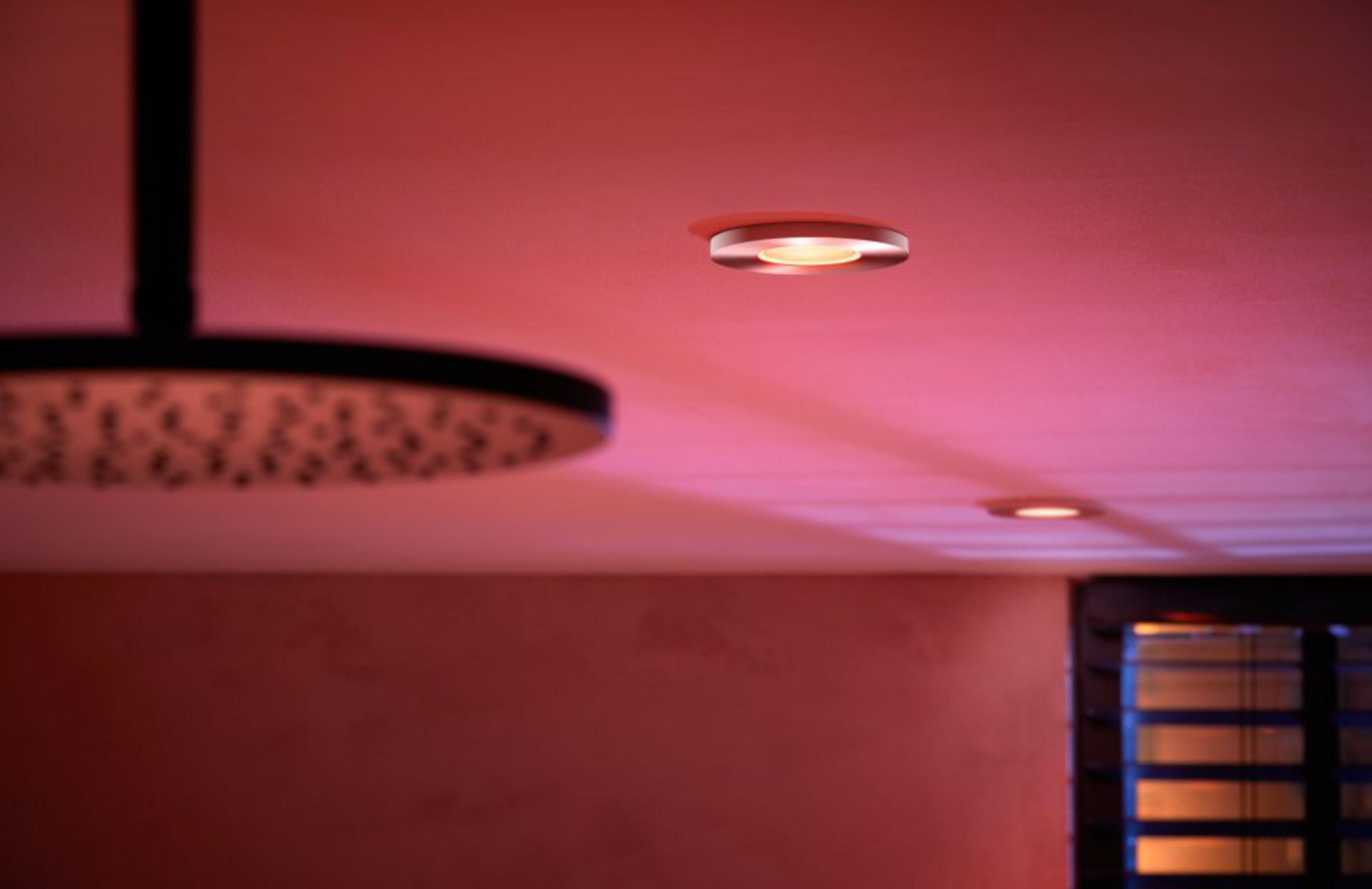 Luci a soffitto con luce rosa sopra una doccia e una finestra.