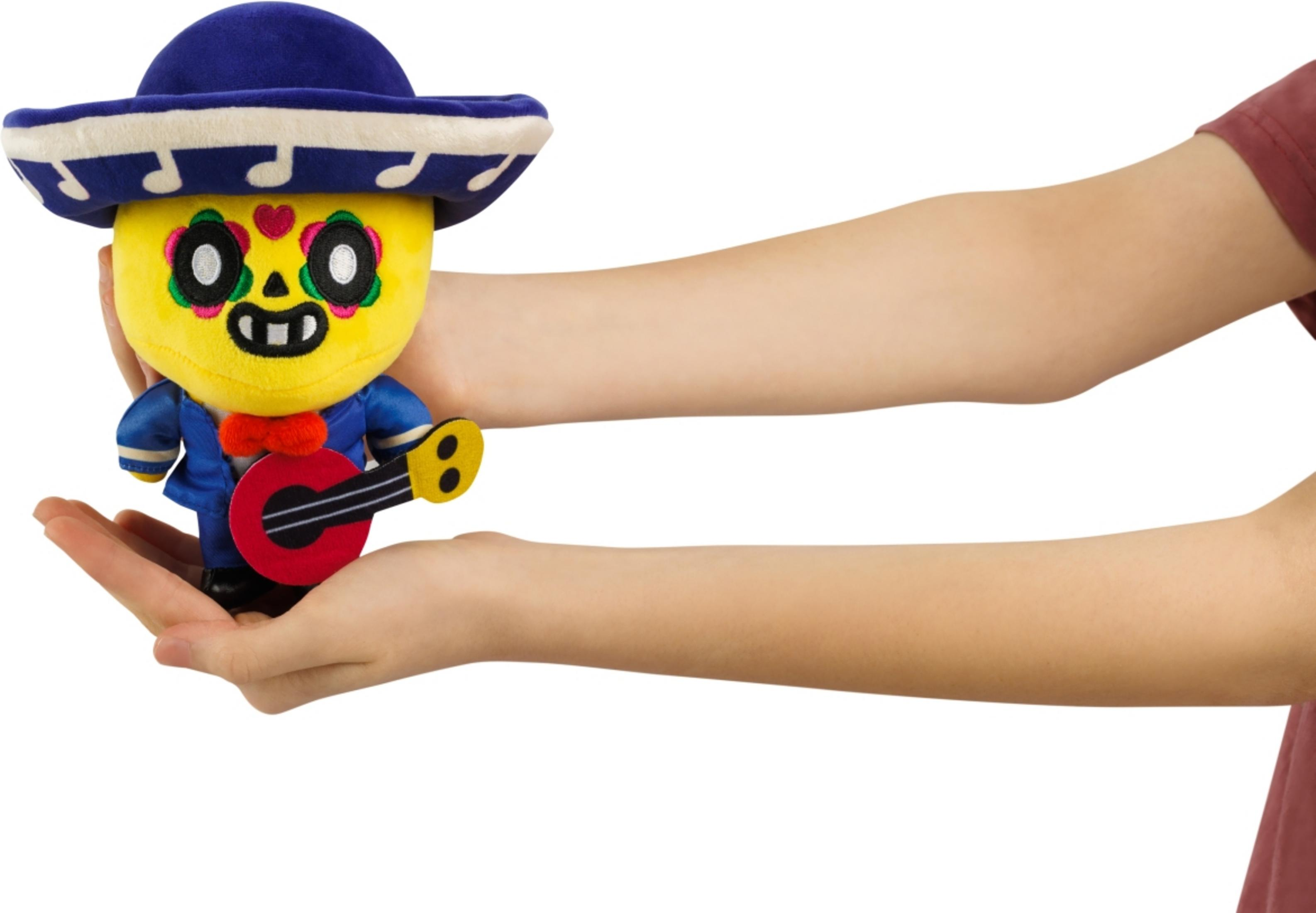 Ein gelbes Stofftier mit Sombrero und Gitarre wird von Händen gehalten.