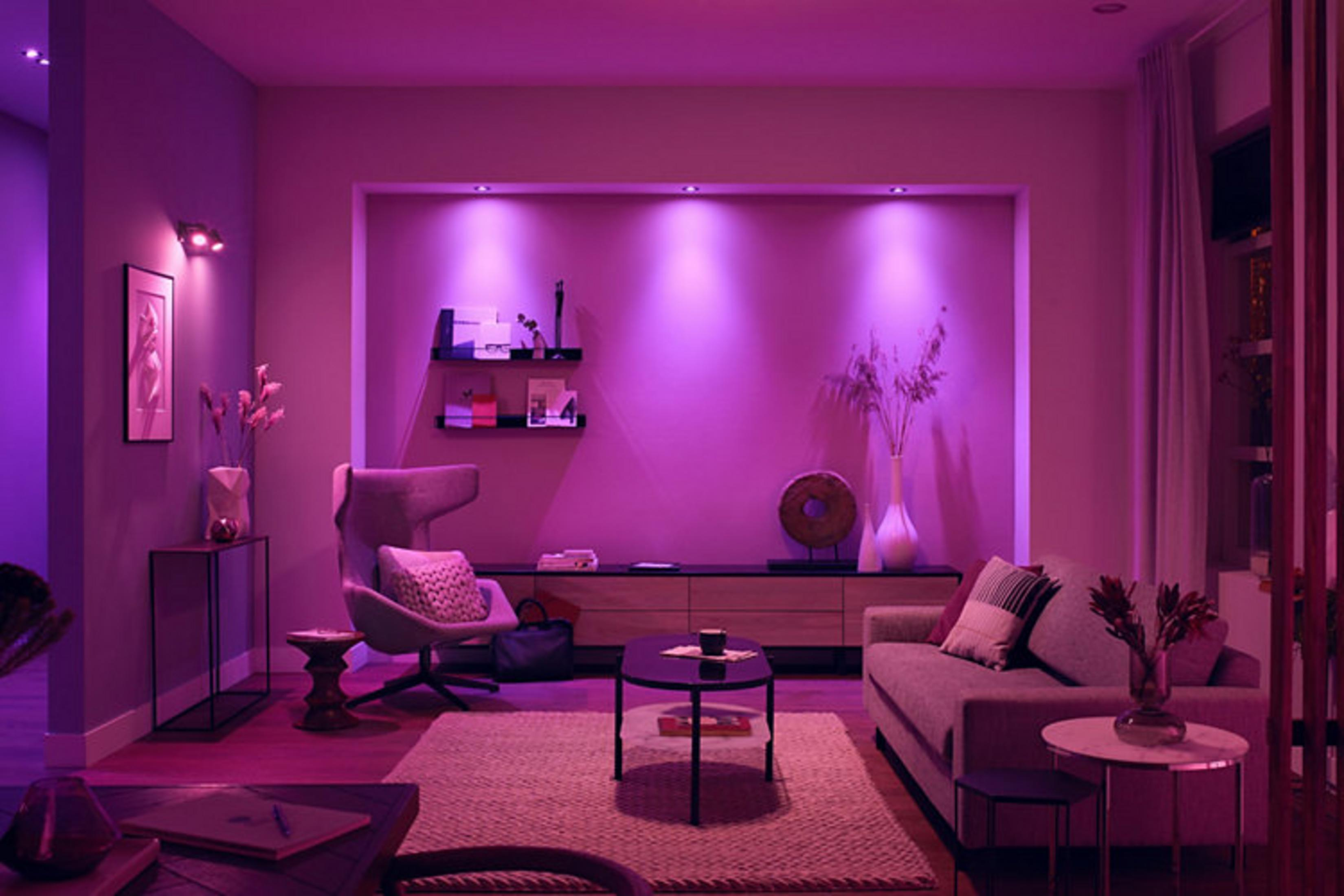 Un soggiorno con illuminazione viola, divano, poltrona e tavolino.