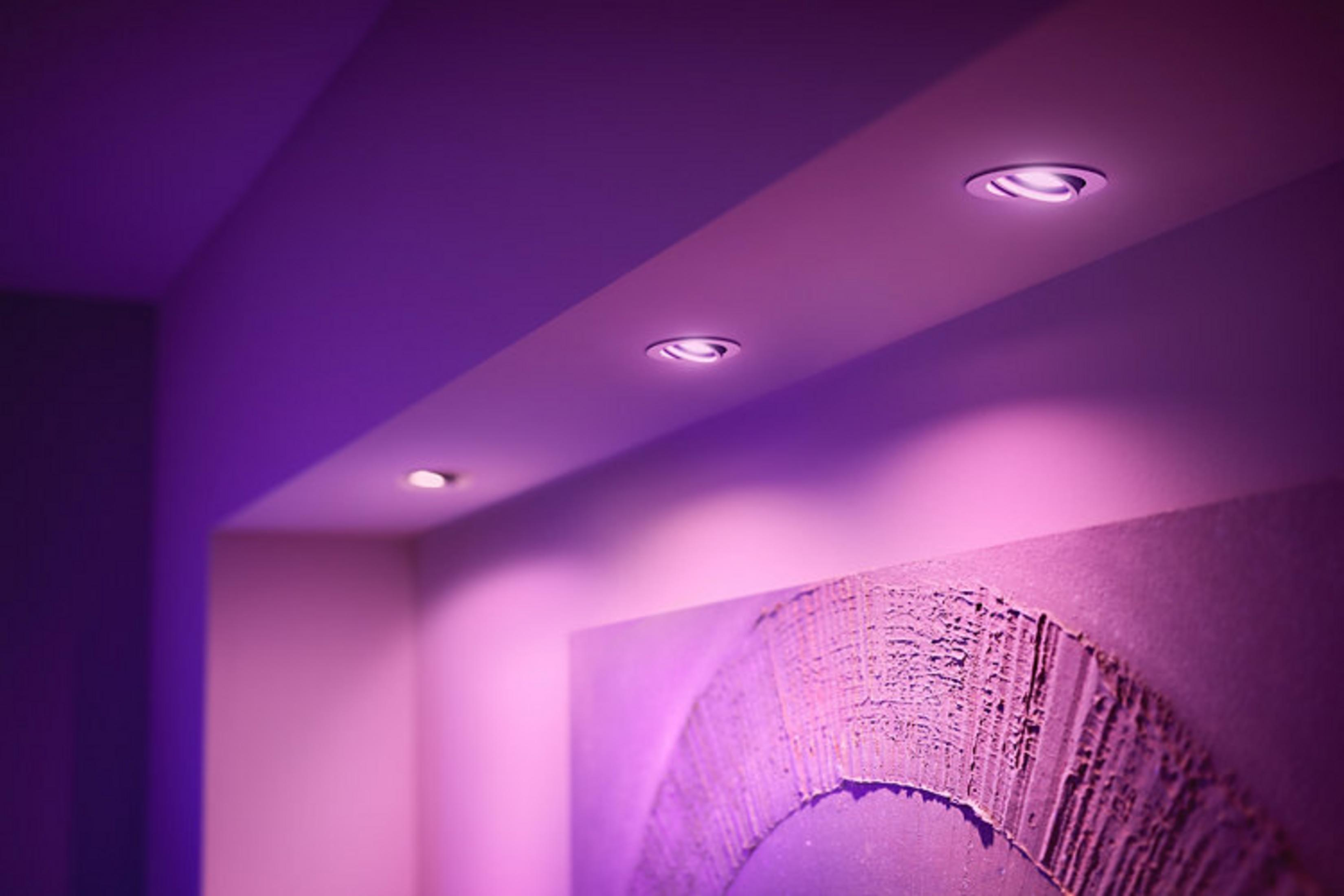Diverse luci da incasso illuminano una parete con opere d'arte viola.