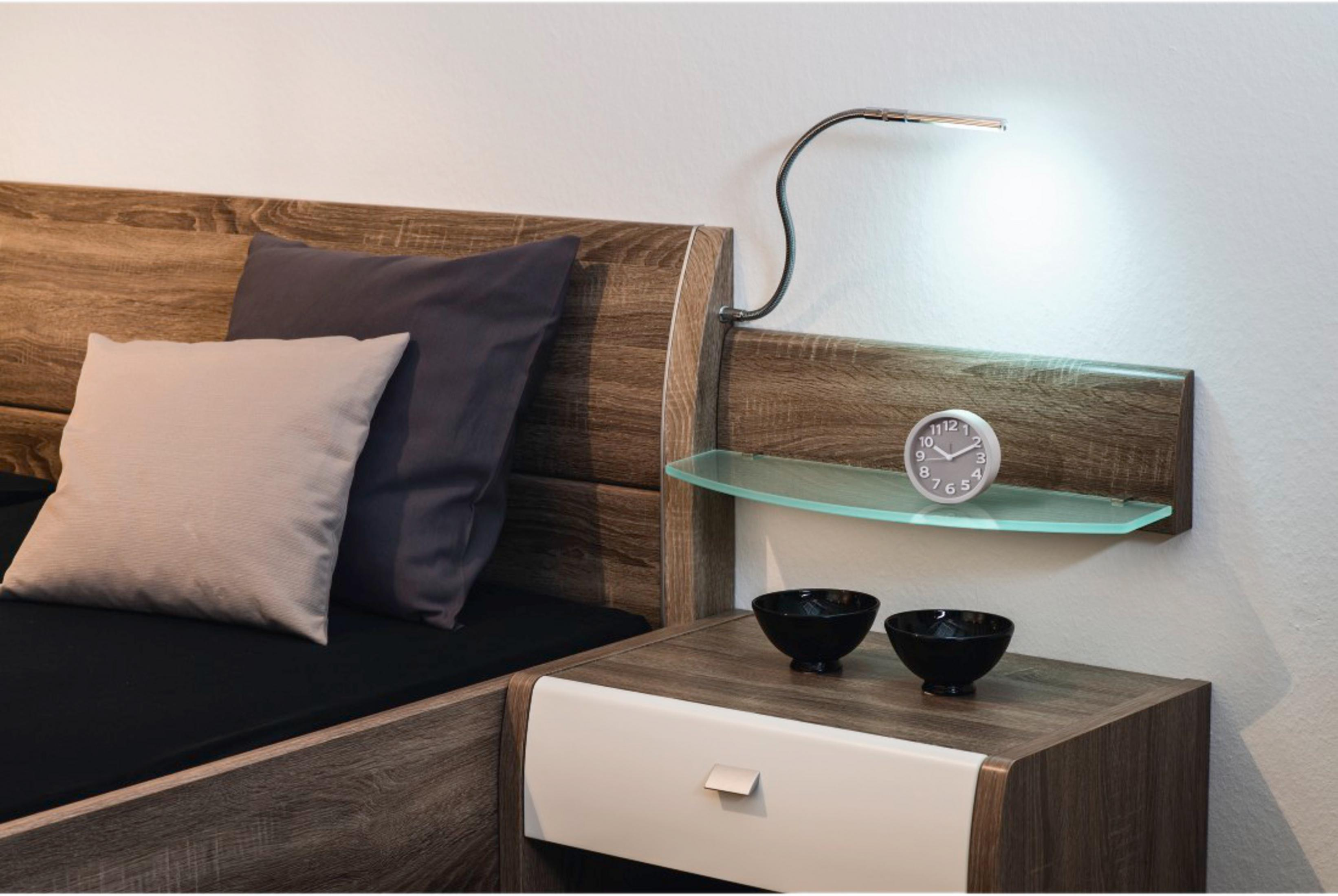 Drewniany stolik nocny z szufladą, szklaną półką, zegarem, miskami i lampą.