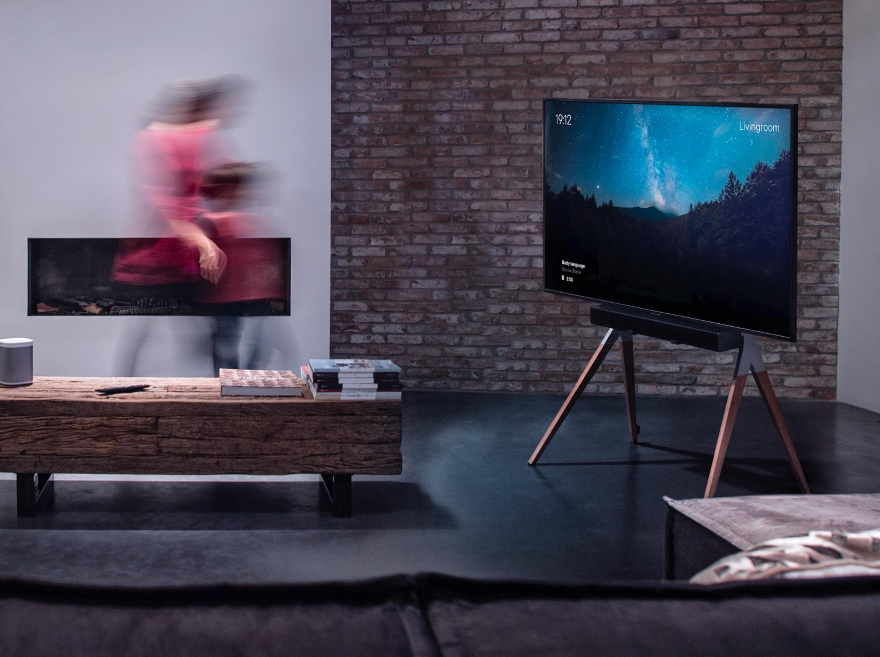 Ein Wohnzimmer mit Kamin, Holztisch und Fernseher, der einen Sternenhimmel zeigt.