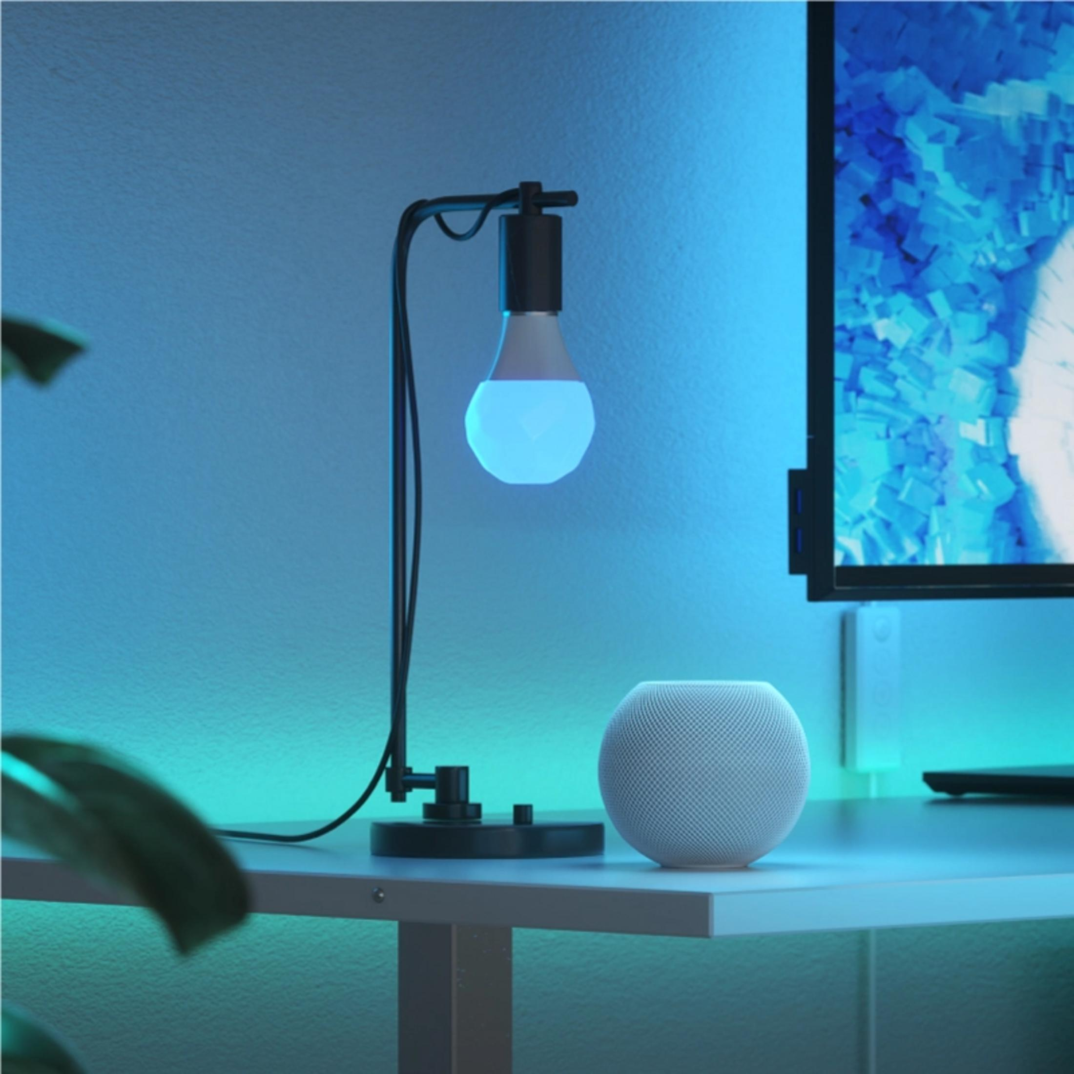 Un altoparlante bianco e una lampada con luce blu su una scrivania.
