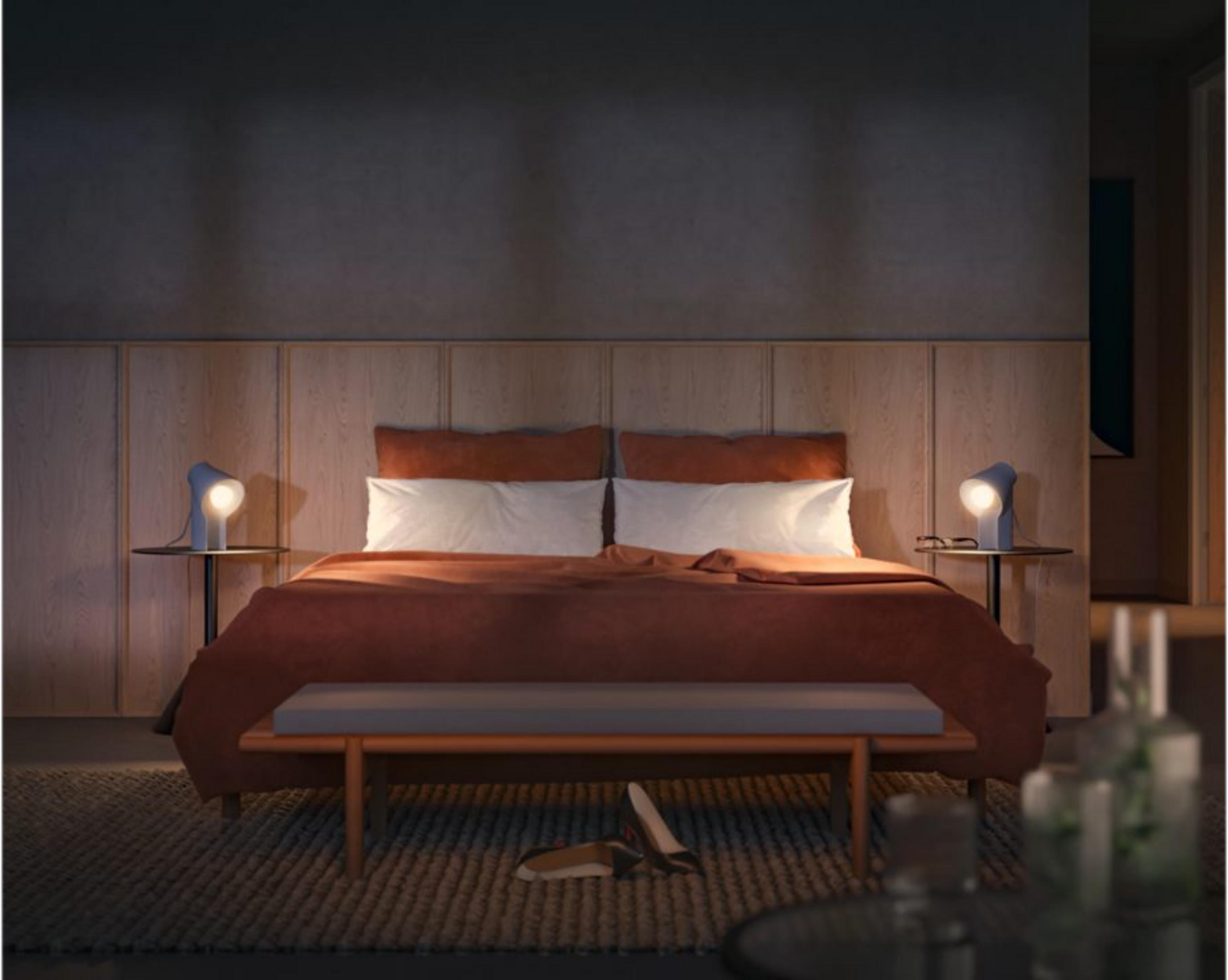 Łóżko z brązową kołdrą, białymi poduszkami i dwiema lampkami nocnymi.