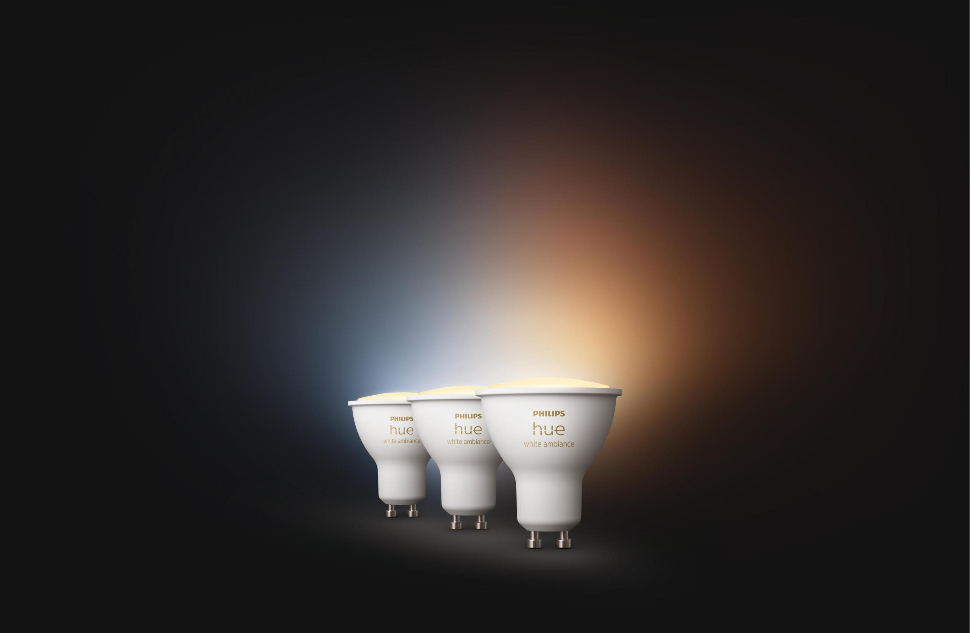 Tre lampadine Philips Hue bianche con scritte dorate su sfondo scuro.