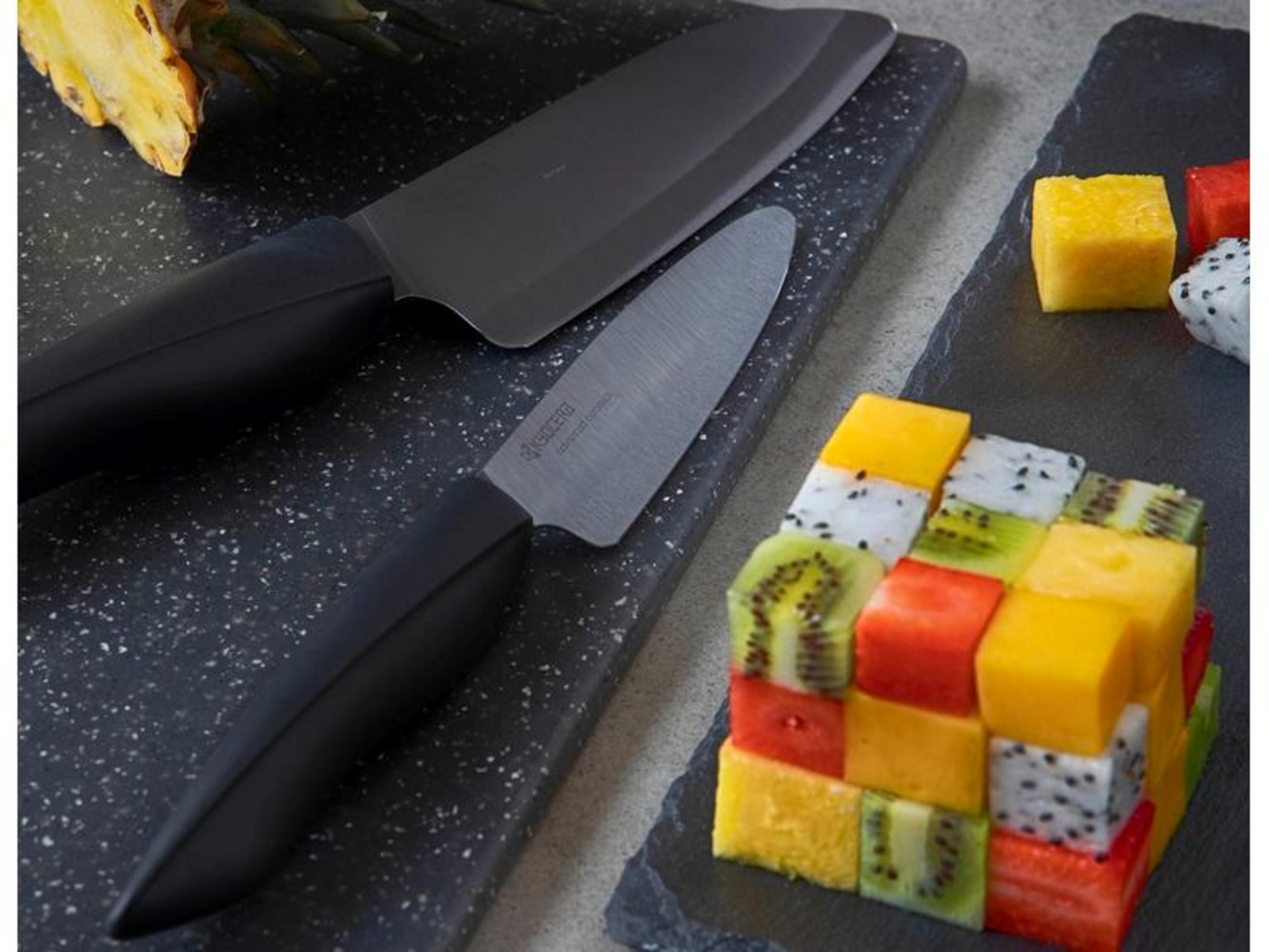 Zwei Messer liegen neben gewürfeltem Obst: Mango, Erdbeere, Kiwi und Drachenfrucht.