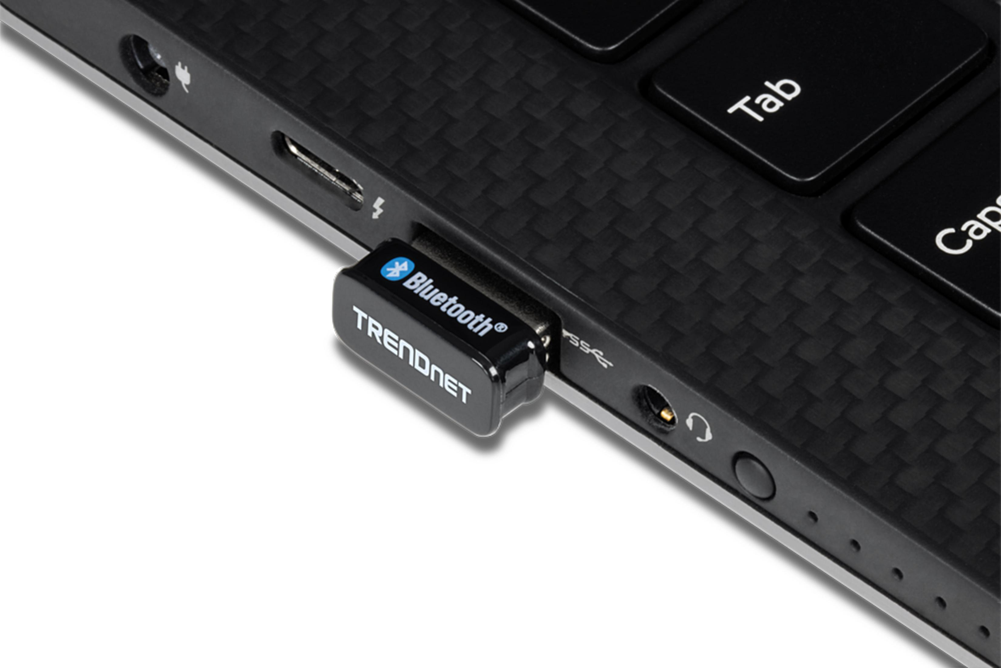 Un adaptateur Bluetooth noir branché sur un port d'ordinateur portable. Clavier en arrière-plan.