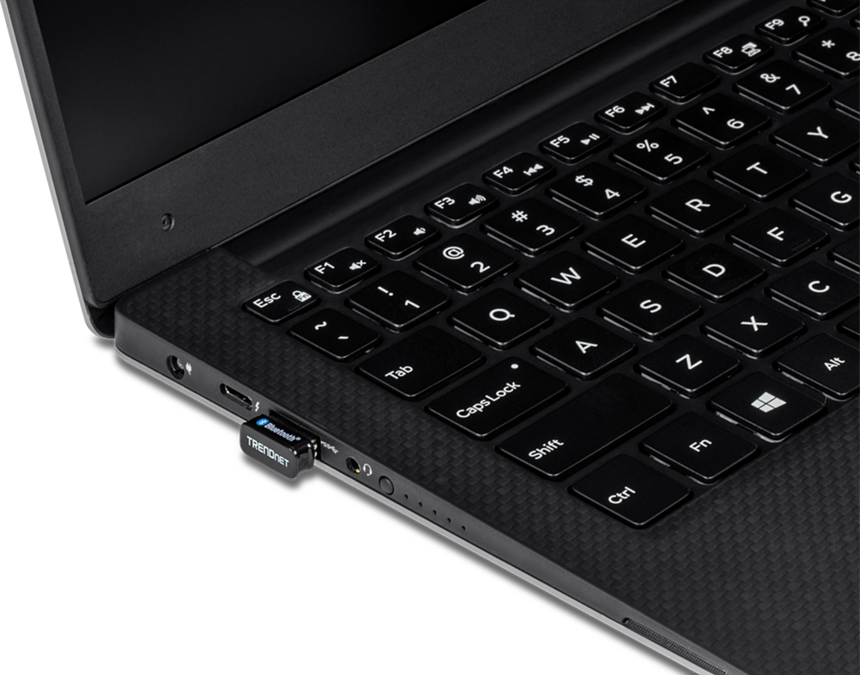 Un adaptateur USB Bluetooth bleu est branché sur un ordinateur portable. Gros plan.