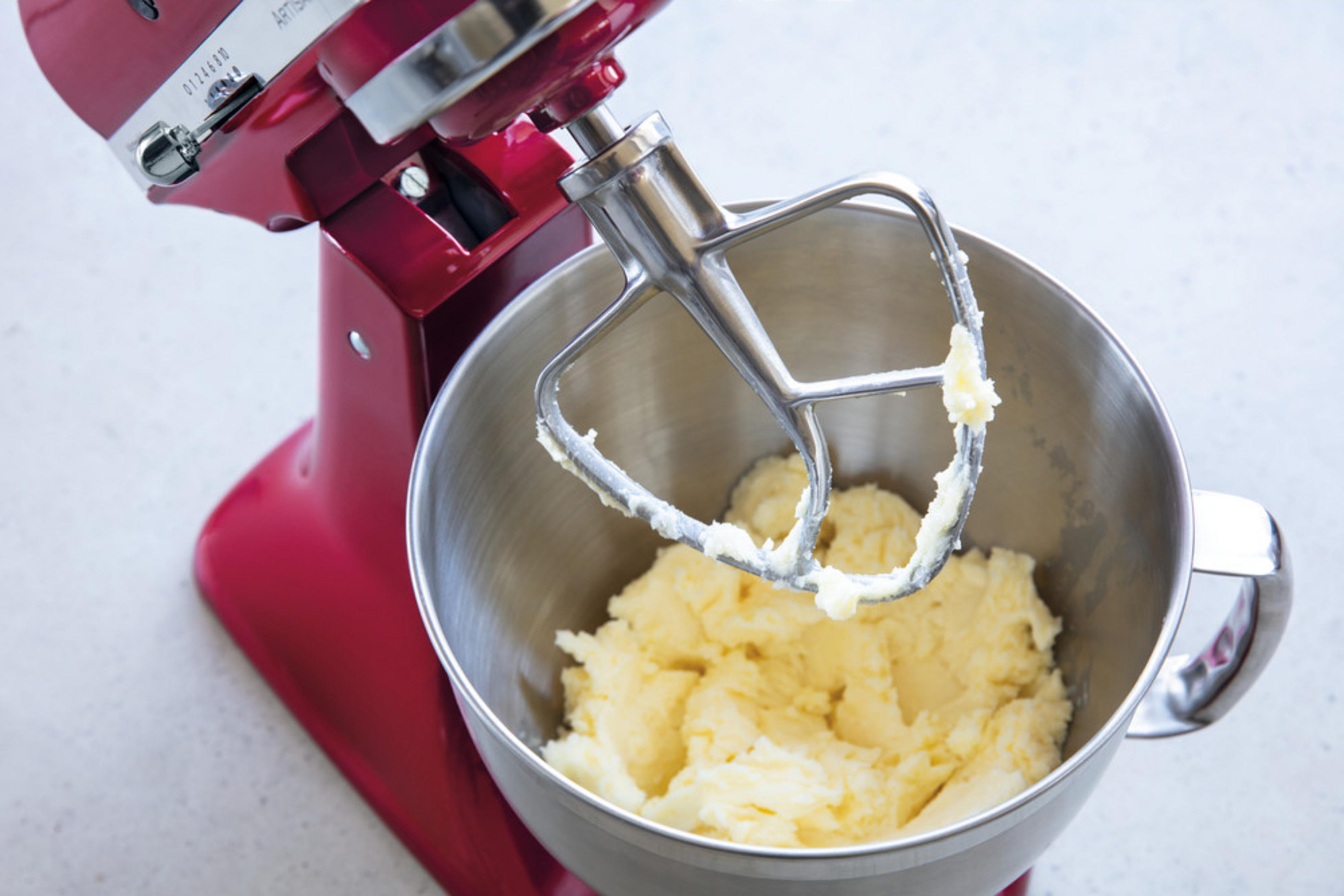 Ein roter Standmixer mit Rührschüssel, gefüllt mit hellgelber Masse.