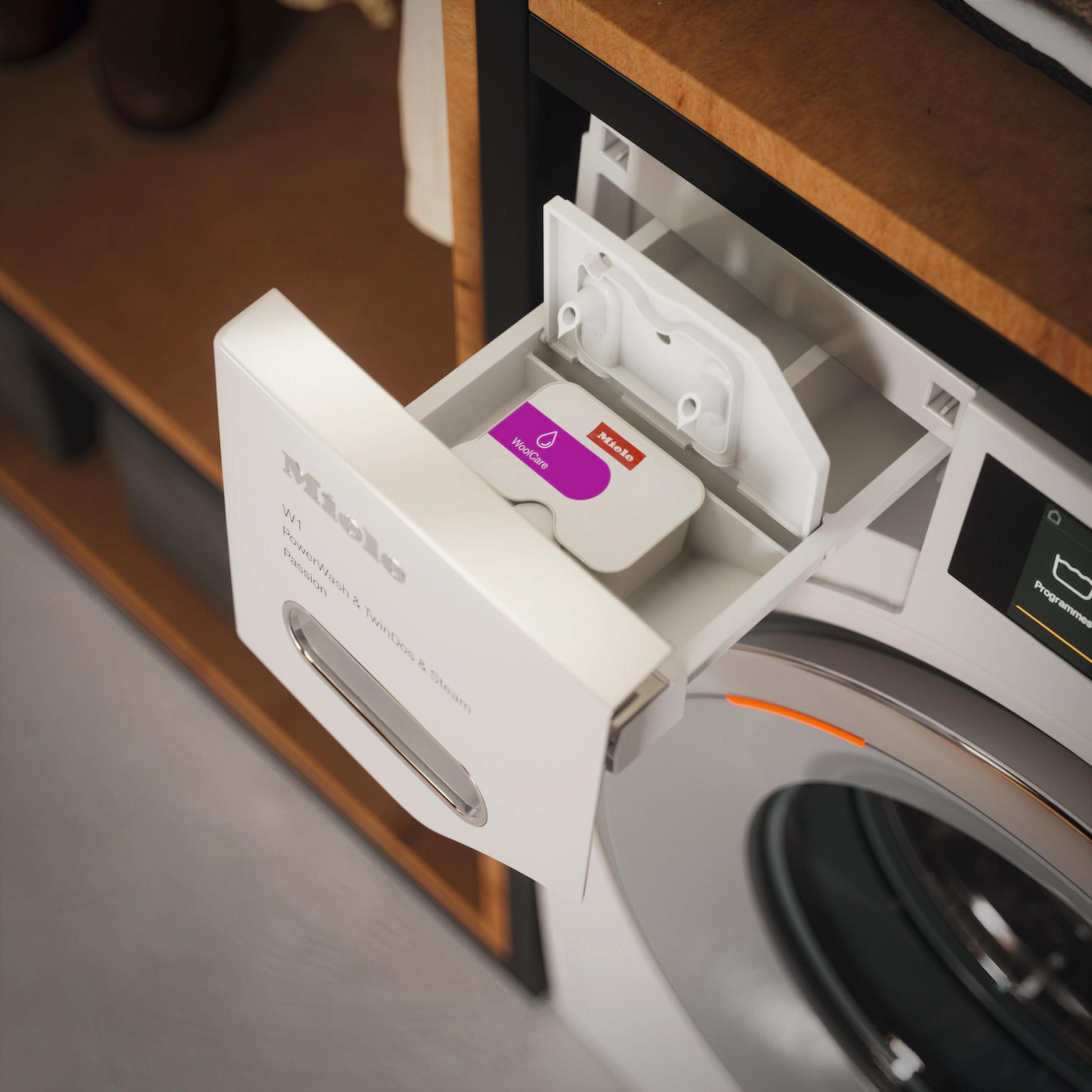 Eine Schublade einer Miele Waschmaschine mit einer "WoolCare"-Kapsel.