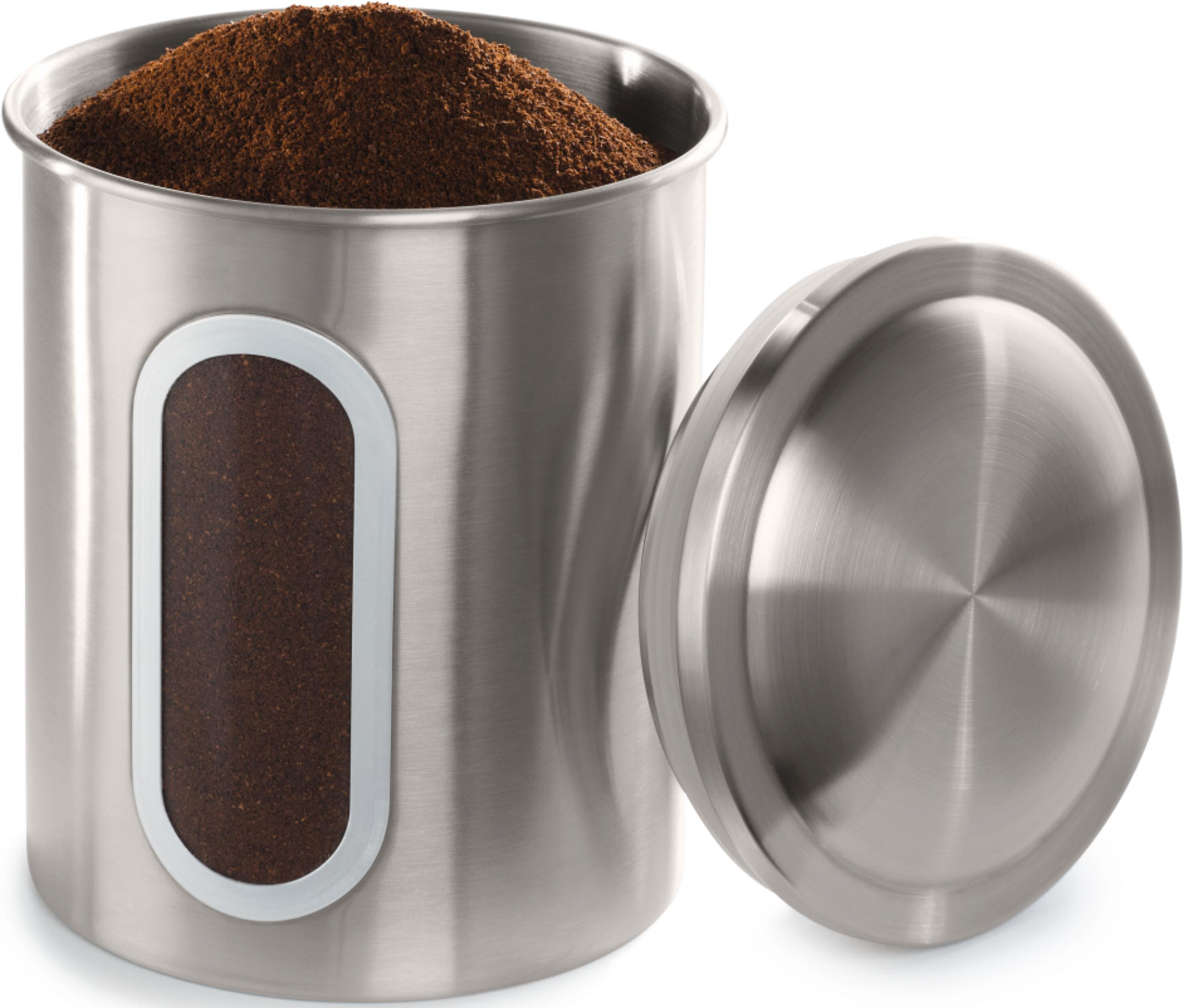 A silver container with brown coffee grounds and its lid beside it.